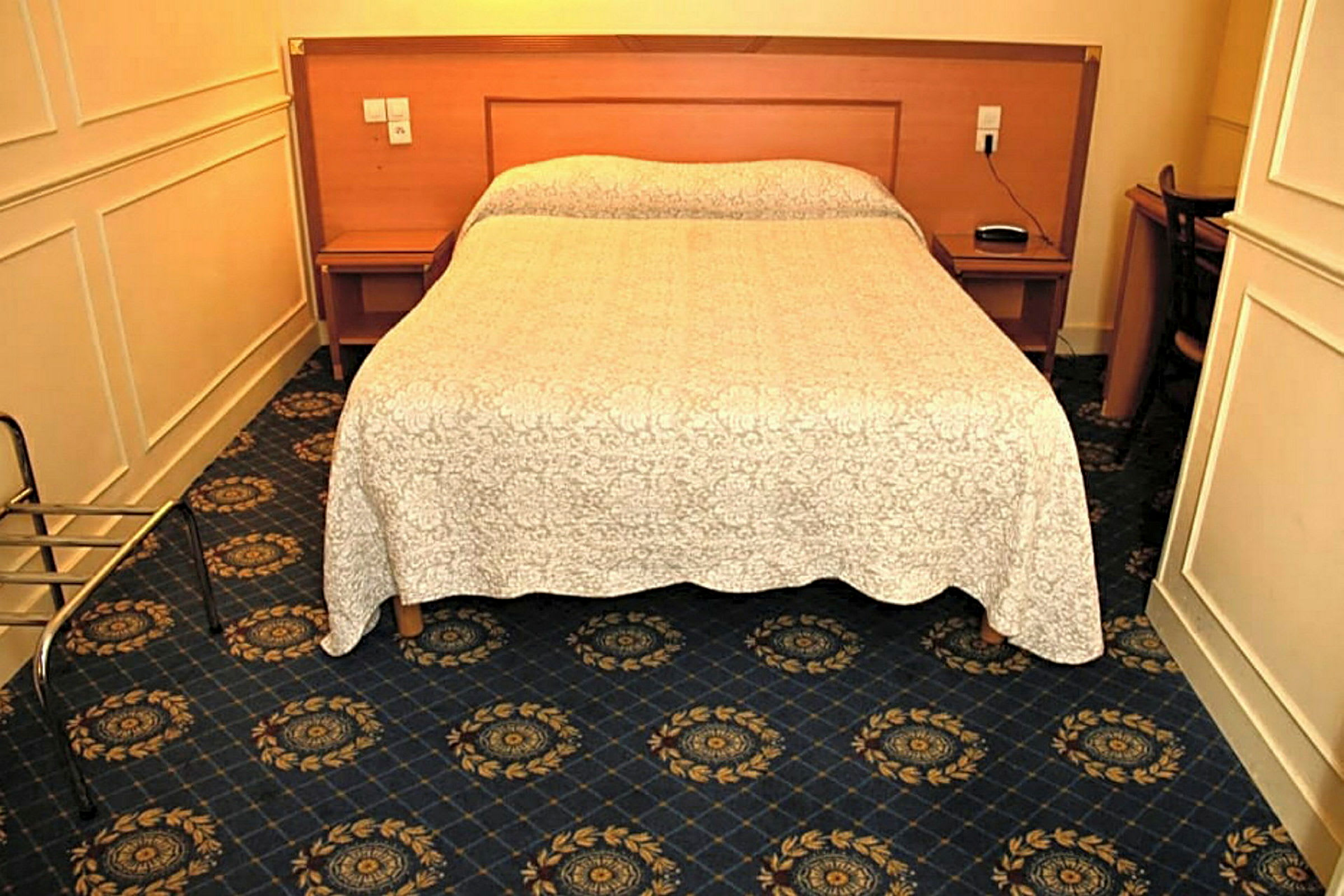 Hotellihuone, jossa parivuode, tummansininen matto ja valkoinen päiväpeite. (Tekoälyn luoma teksti)