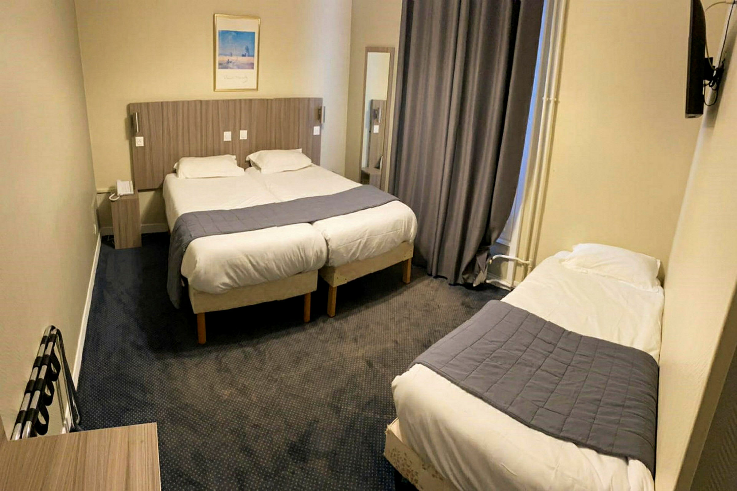 Hotellihuone, jossa kaksi yhteen liitettyä yhden hengen vuodetta ja yksi erillinen yhden hengen vuode. (Tekoälyn luoma teksti)