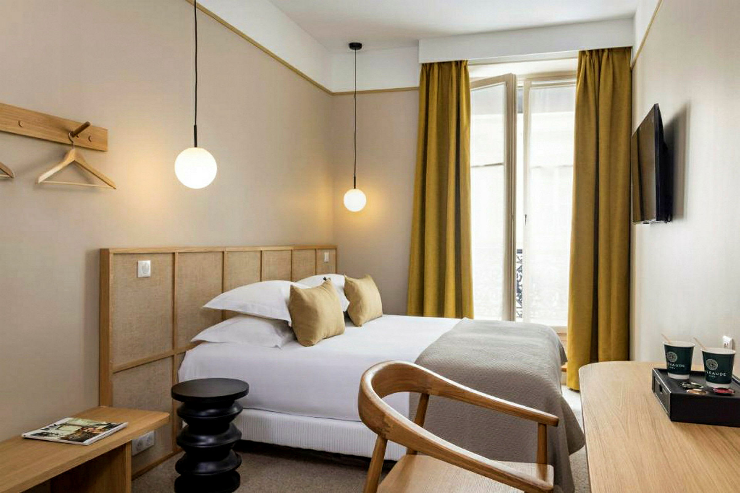 Moderni hotellihuone, jossa on sänky, kirjoituspöytä ja seinälle kiinnitetty televisio. (Tekoälyn luoma teksti)