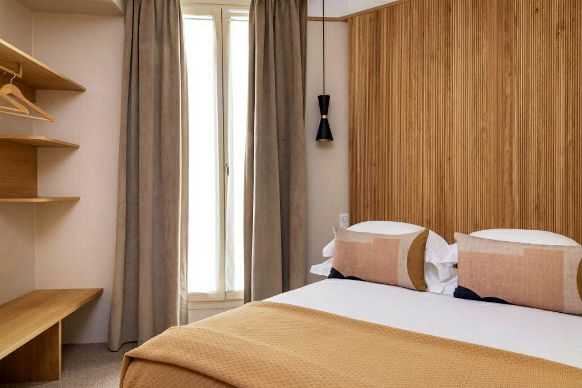 Hotellihuone, jossa on sänky, puupaneeliseinä ja ikkuna verhoilla. (Tekoälyn luoma teksti)