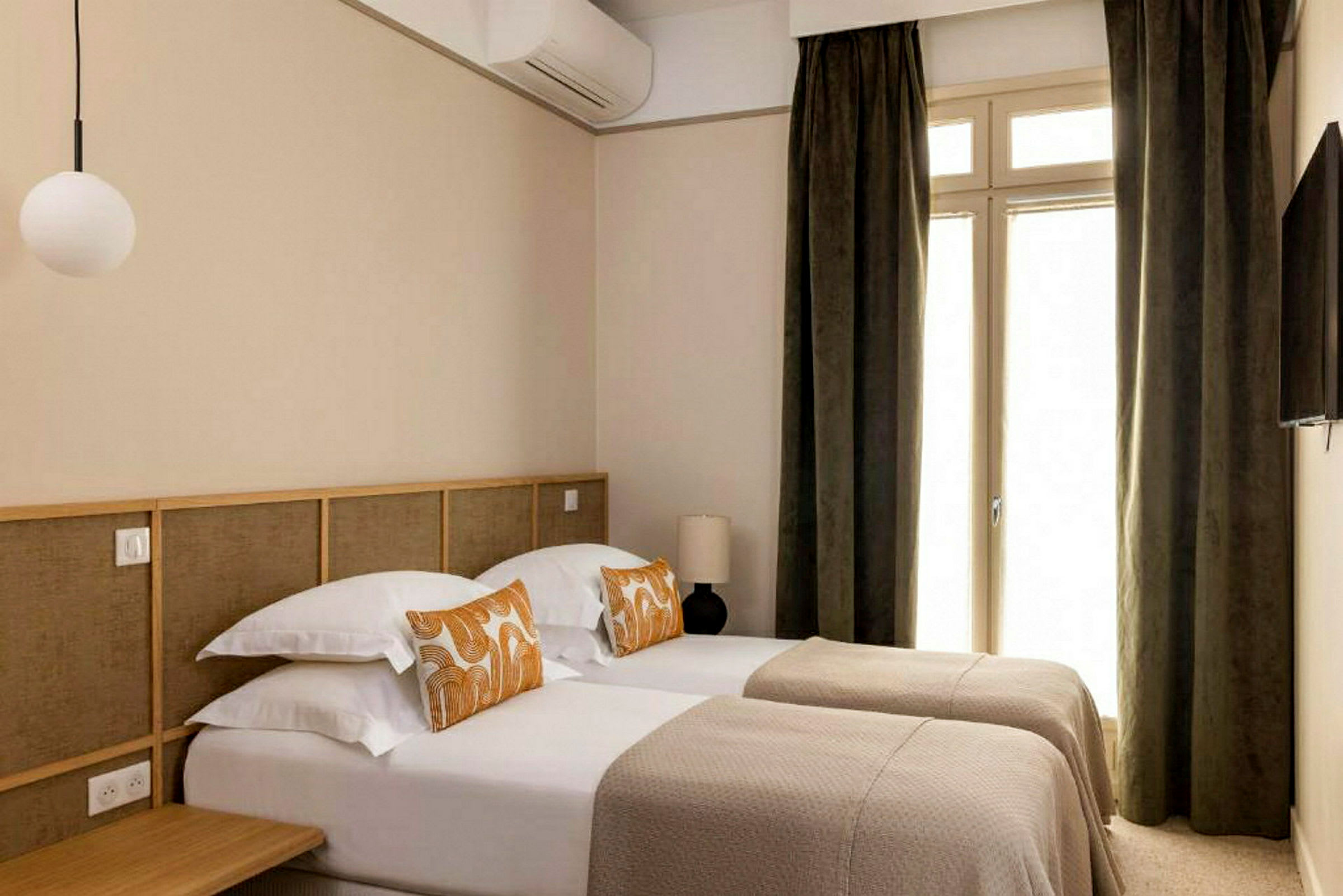 Kuva hotellihuoneesta, jossa on kaksi yhden hengen vuodetta ja ovi verhoineen. (Tekoälyn luoma teksti)