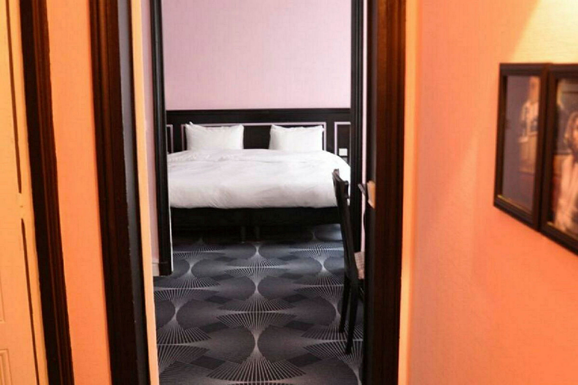 Hotellihuoneen sisustus, jossa sänky näkyy oviaukon läpi. (Tekoälyn luoma teksti)