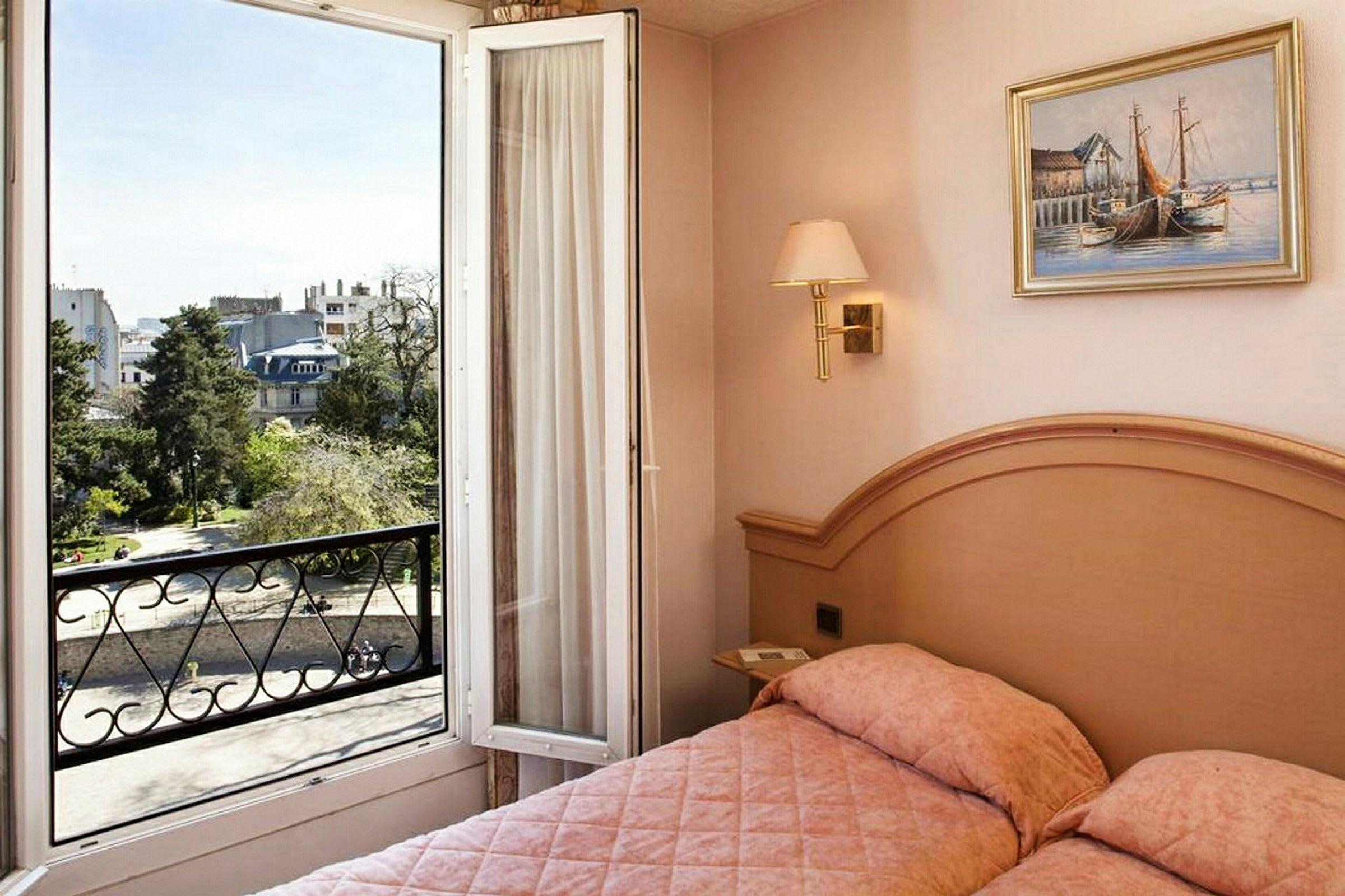 Hotellihuone, jossa on sänky ja avoin parvekkeen ovi, josta avautuu näkymä kaupunkiin ja viheralueelle. (Tekoälyn luoma teksti)