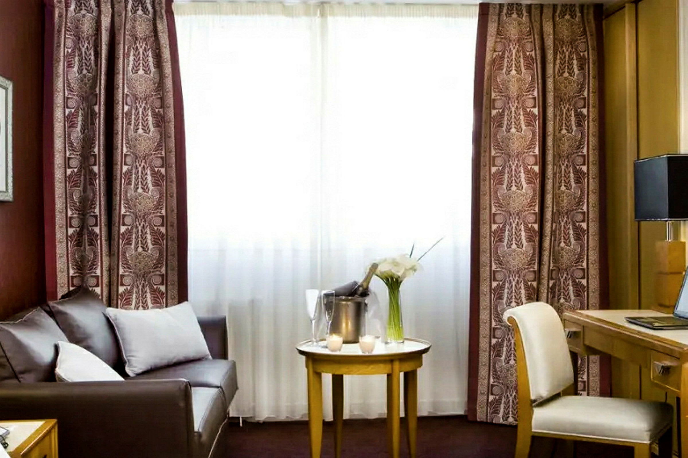 Hotellihuone, jossa on sohva, pöytä ja työskentelytila. (Tekoälyn luoma teksti)
