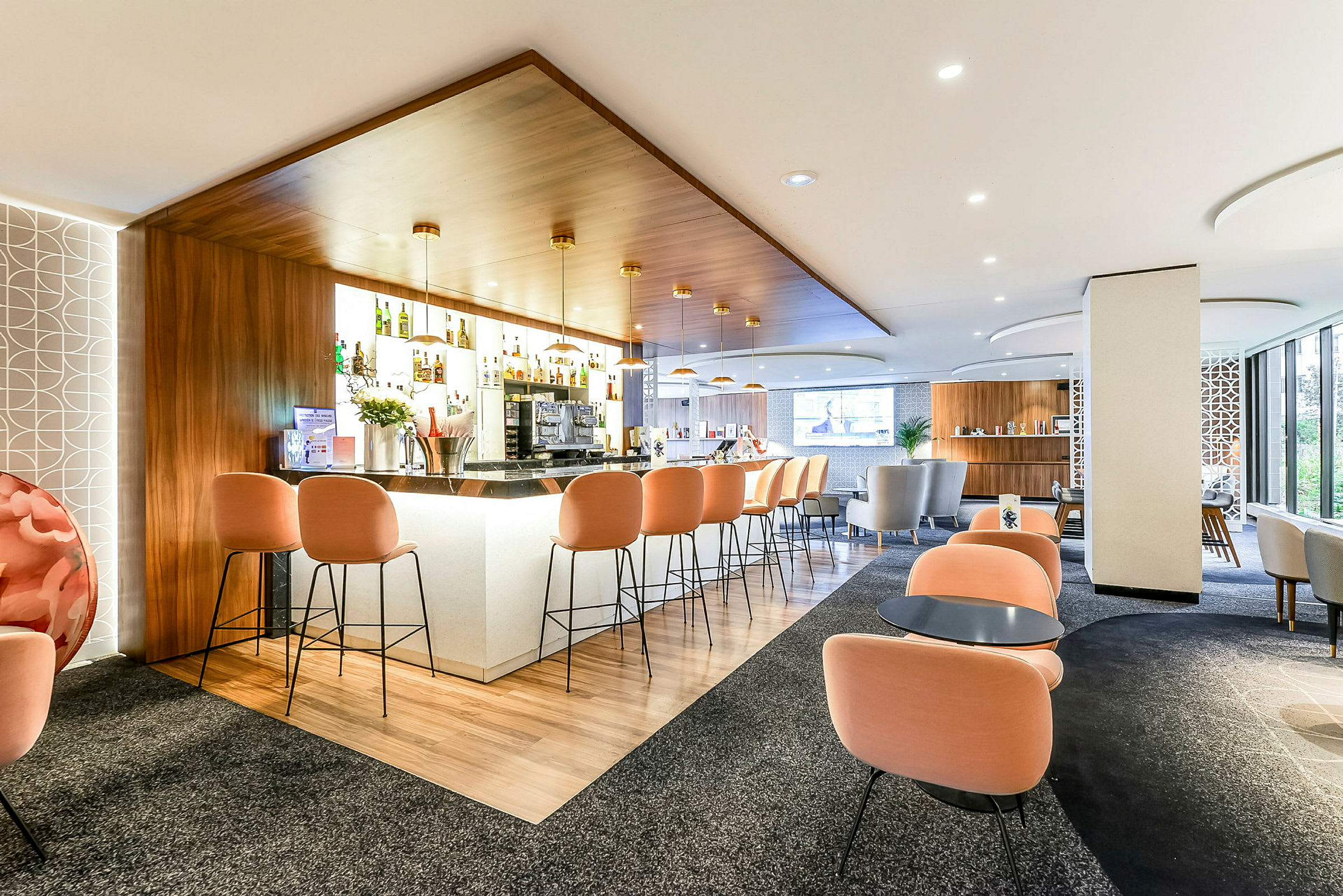 Moderni hotellibaari, jossa on oranssit tuolit ja tyylikäs muotoilu. (Tekoälyn luoma teksti)