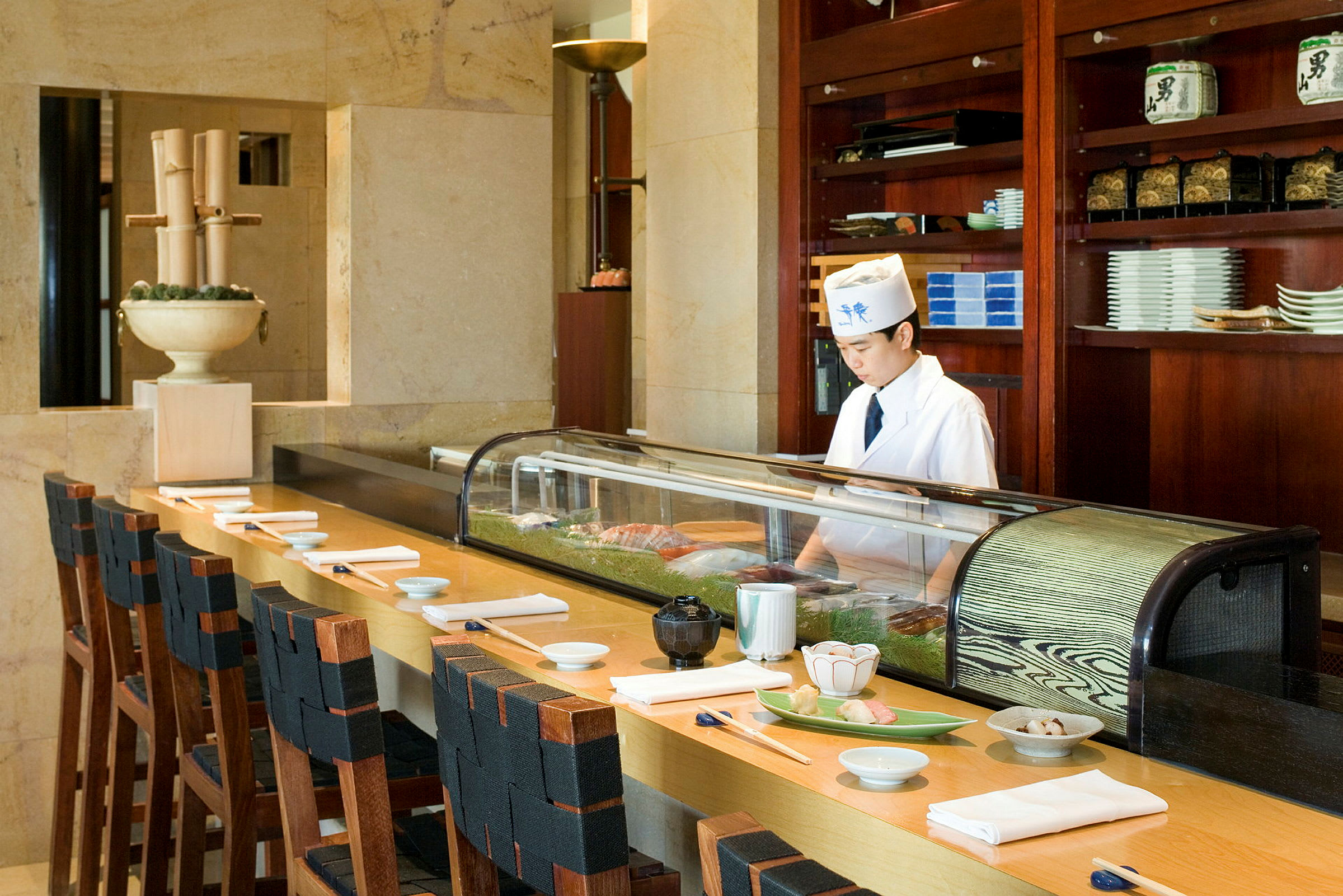 Sushi-baari, jonka tiskillä on tuoleja ja valmiina lautasia sekä syömäpuikkoja. (Tekoälyn luoma teksti)