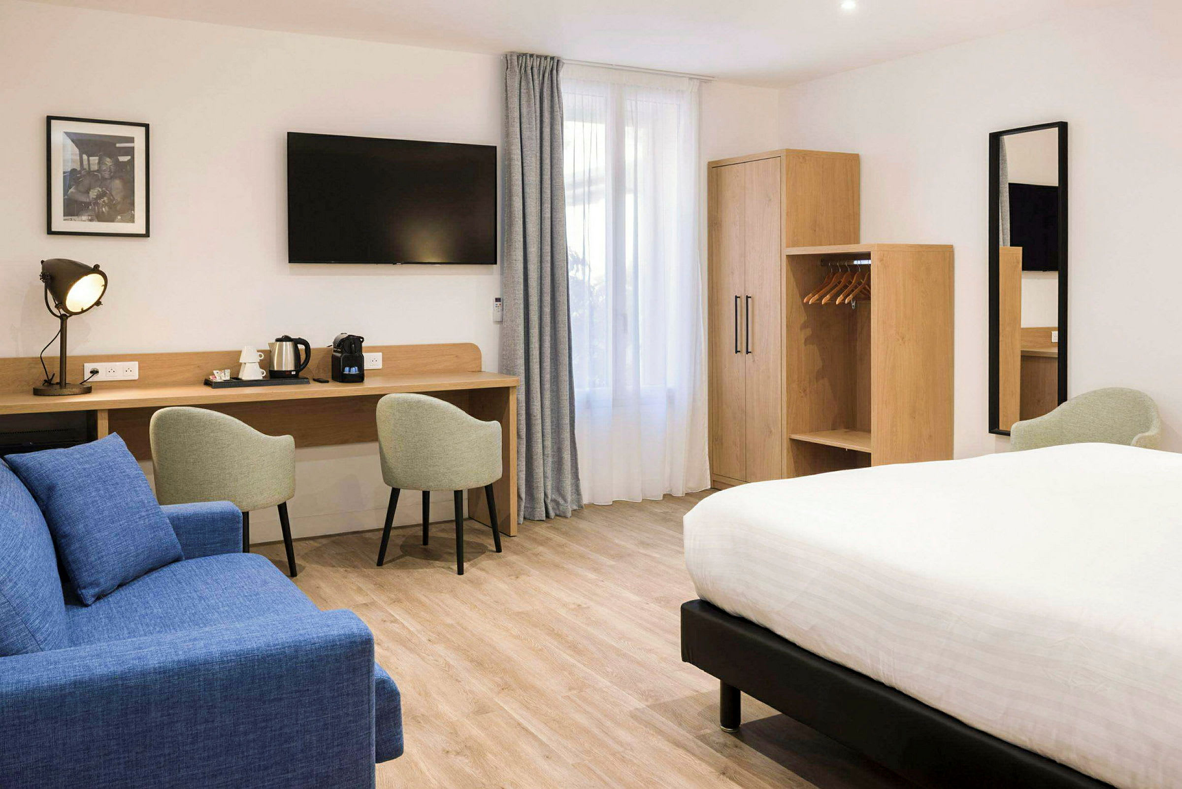 Hotellihuone, jossa parivuode, istuimet, työpöytä ja vaatekaappi. (Tekoälyn luoma teksti)