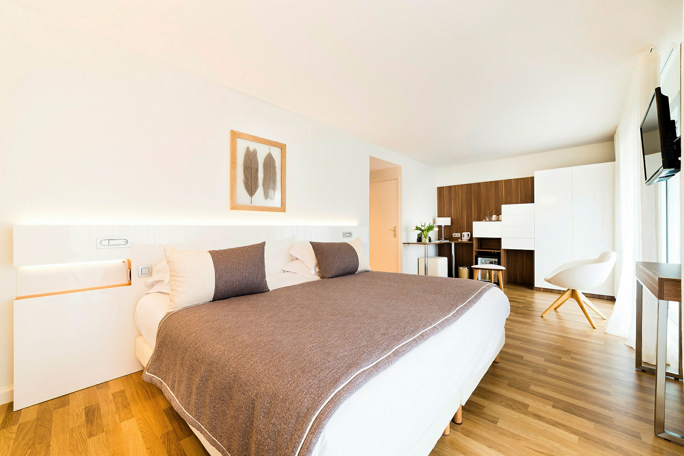Nykyaikainen hotellihuone, jossa on iso sänky, minimalistinen sisustus ja puukalusteet. (Tekoälyn luoma teksti)