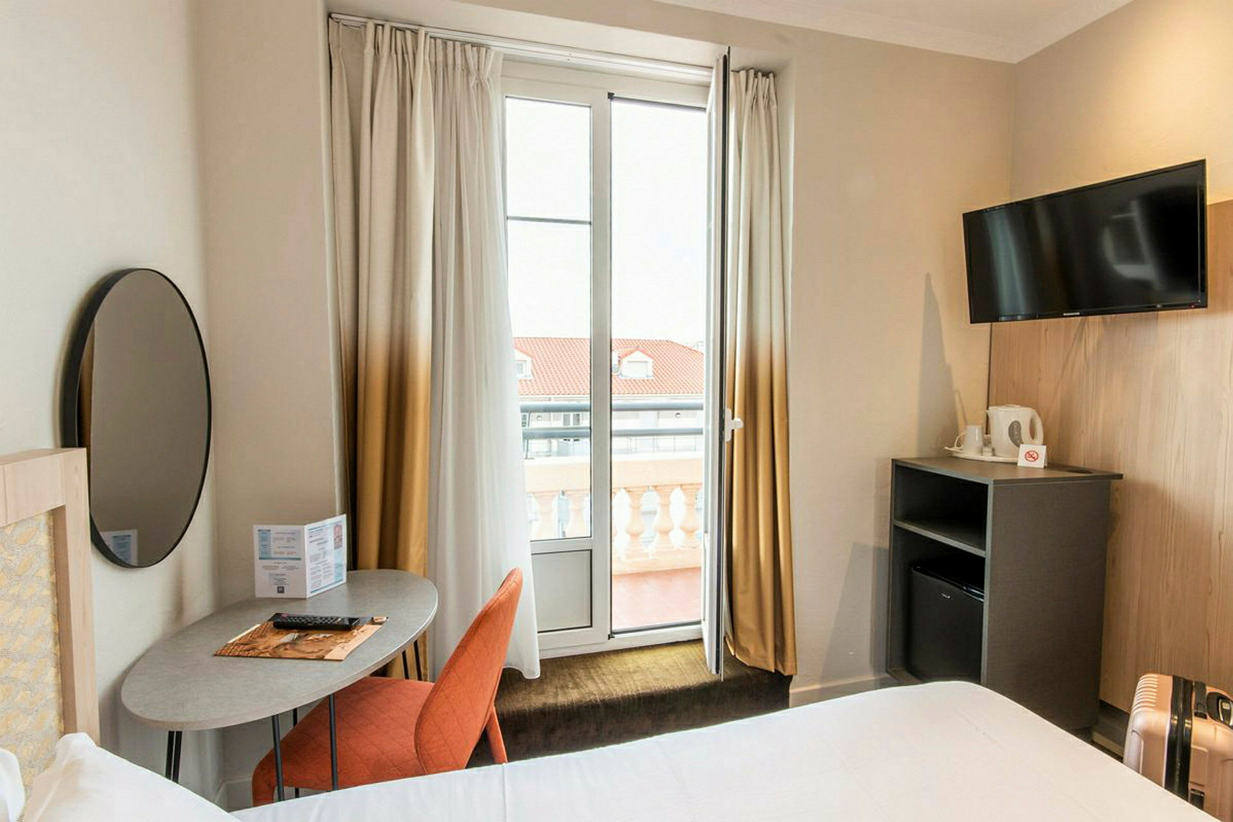 Hotellihuone, jossa on moderni sisustus, sisältäen kirjoituspöydän, tuolin, television ja parvekkeen. (Tekoälyn luoma teksti)