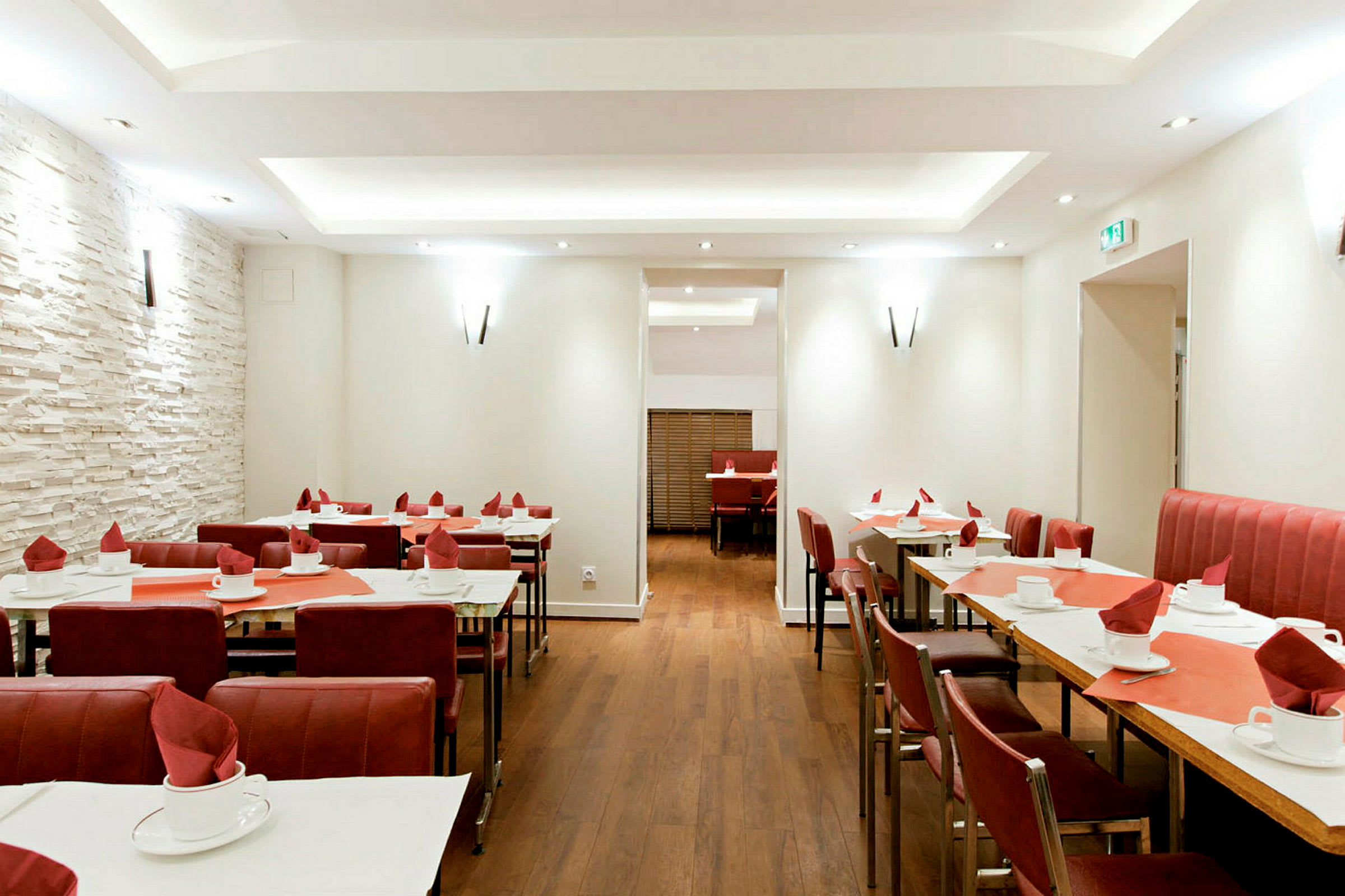 Ravintola, jossa pöydät on katettu ja punaiset tuolit. (Tekoälyn luoma teksti)