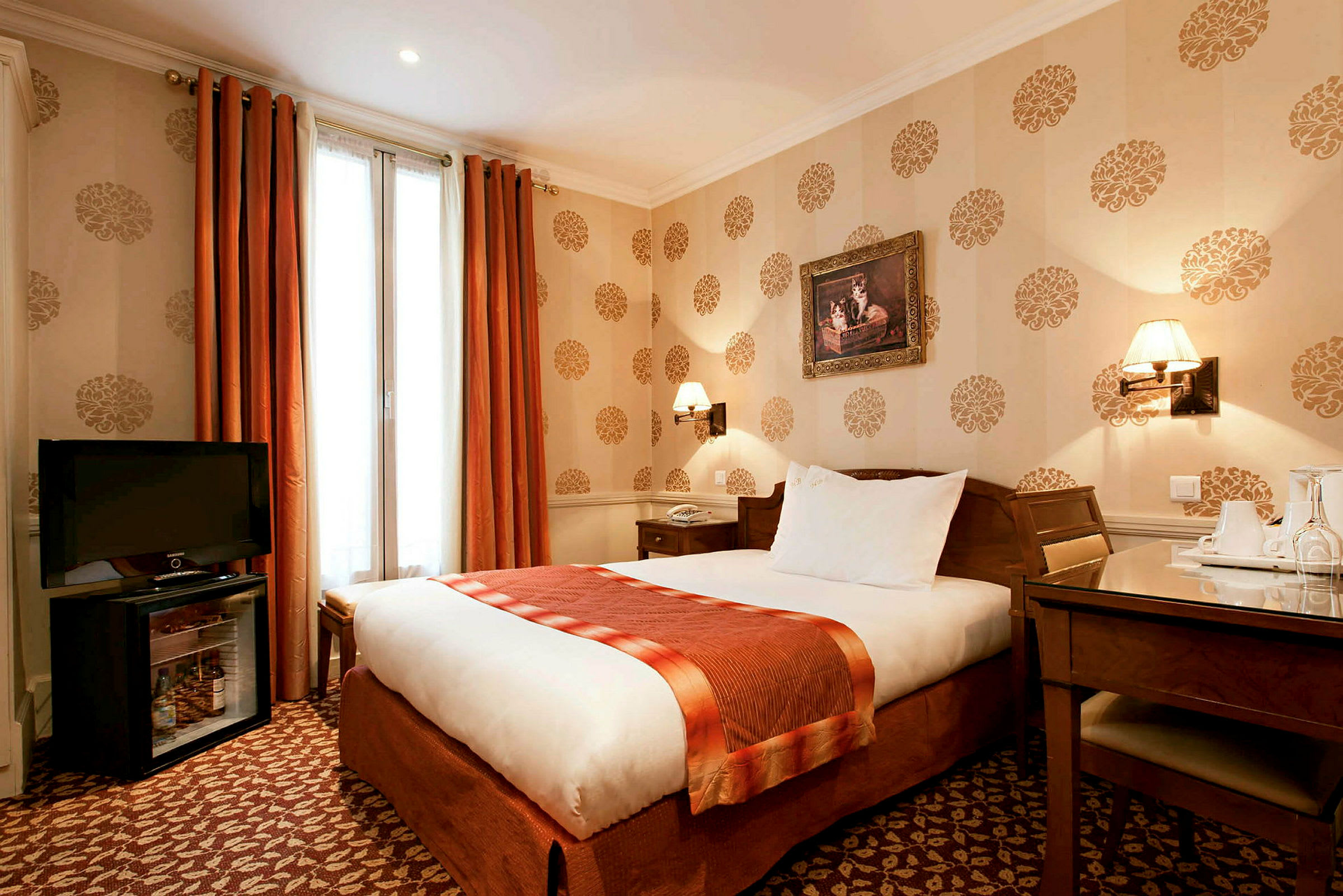 Hotellihuone, jossa on yhden hengen sänky, kirjoituspöytä tuolilla ja televisio kaapin päällä. Huone on koristeltu kuvioidulla tapetilla. (Tekoälyn luoma teksti)