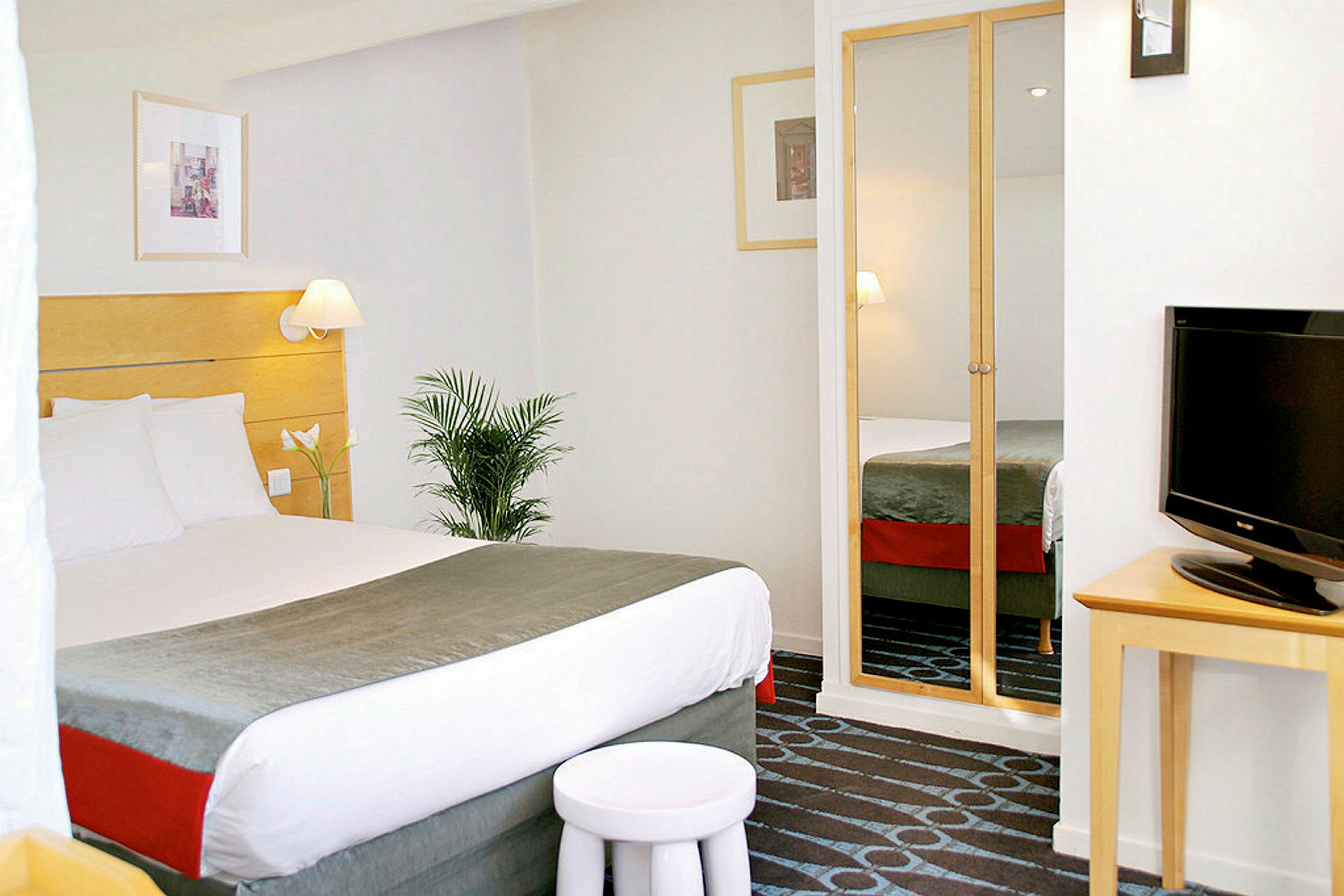 Hotellihuone, jossa parivuode, televisio ja peiliovinen vaatekaappi. (Tekoälyn luoma teksti)
