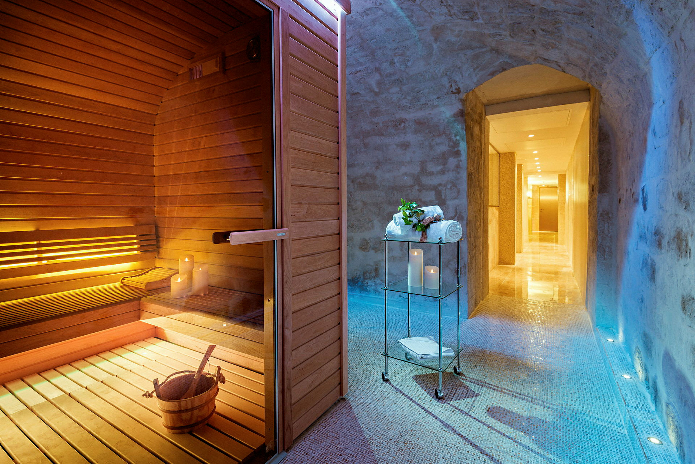 Sauna, jossa on puupaneelit, hylly pyyhkeillä ja kynttilöillä kylpylätilassa. (Tekoälyn luoma teksti)