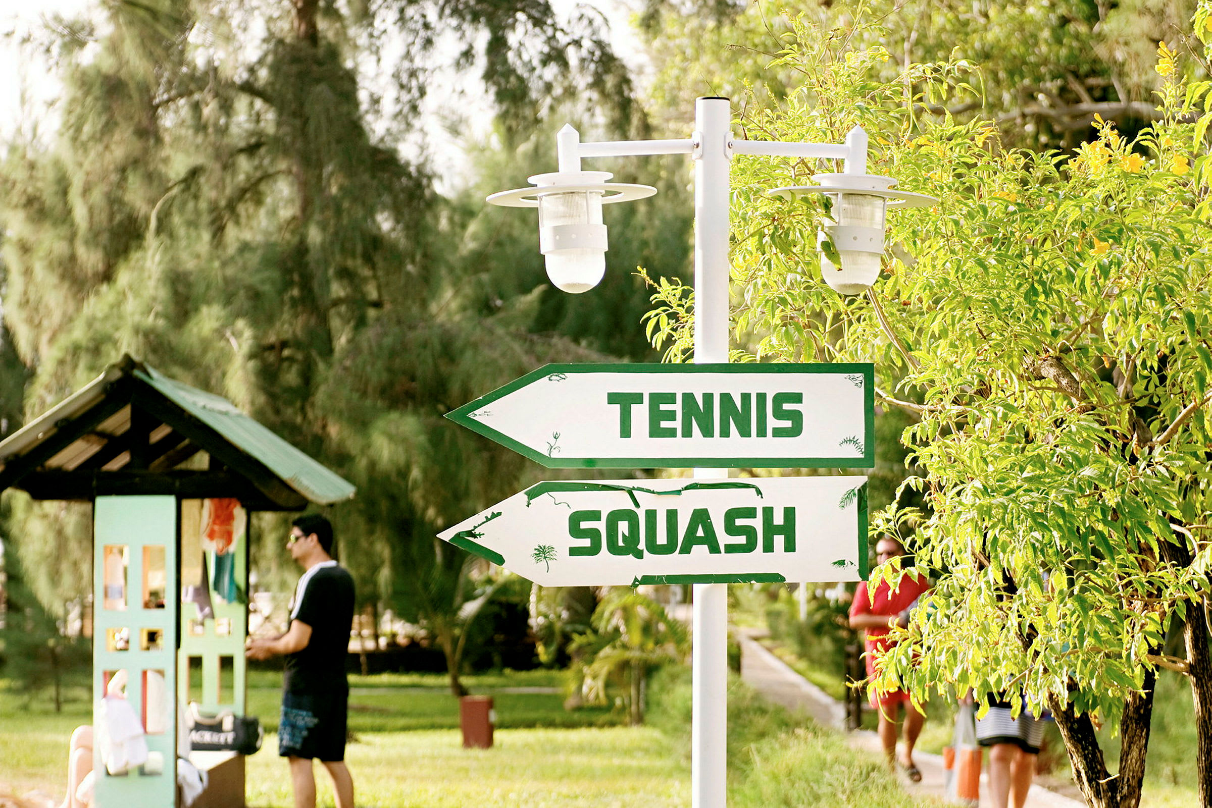 Kyltit, joissa lukee 'Tennis' ja 'Squash', vehreässä ympäristössä. (Tekoälyn luoma teksti)