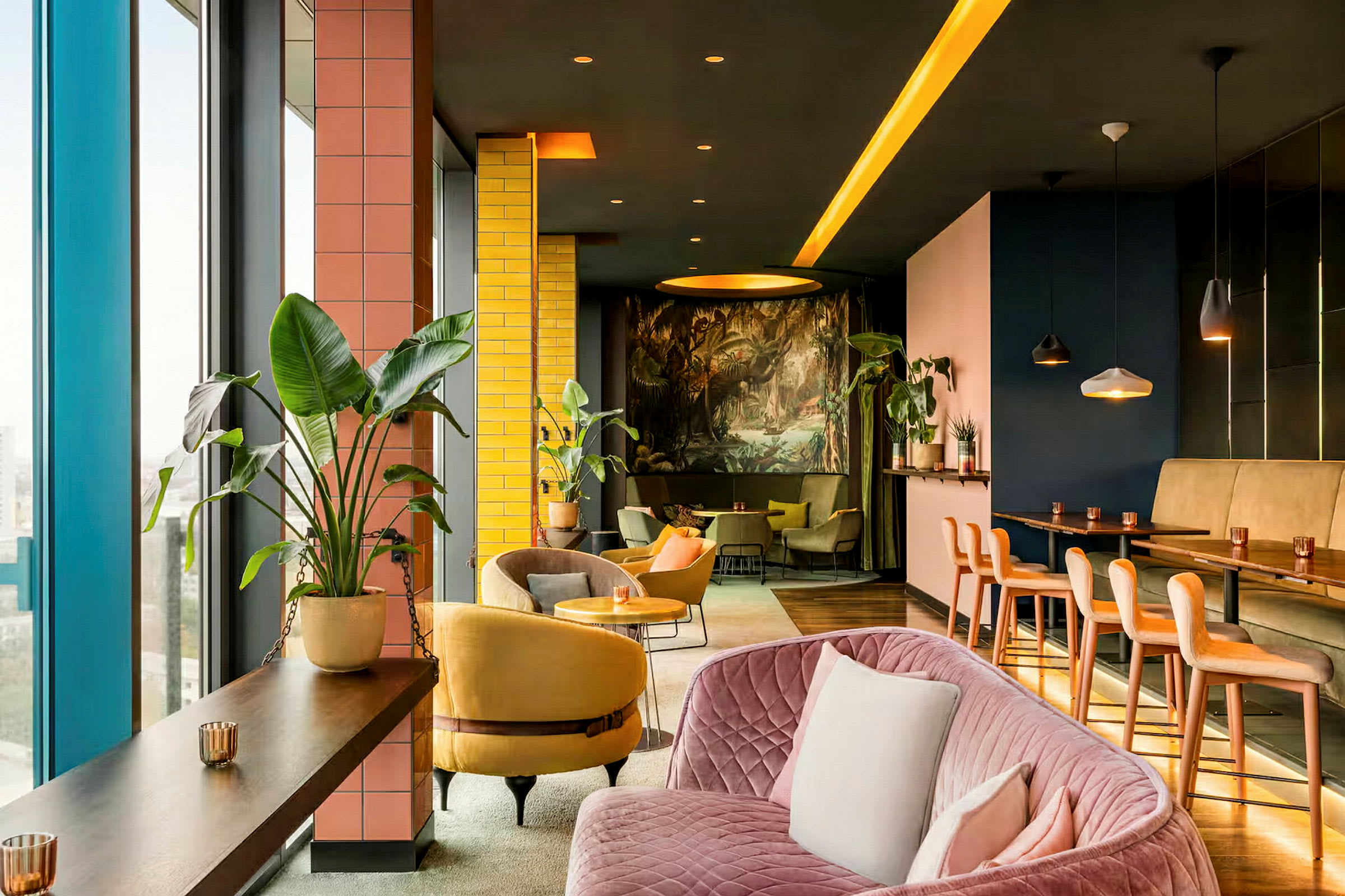 Modernin ja värikkään lounge-tilan sisätila, jossa kasveja, sohvia ja tuoleja sekä korkean pöydän alue. (Tekoälyn luoma teksti)