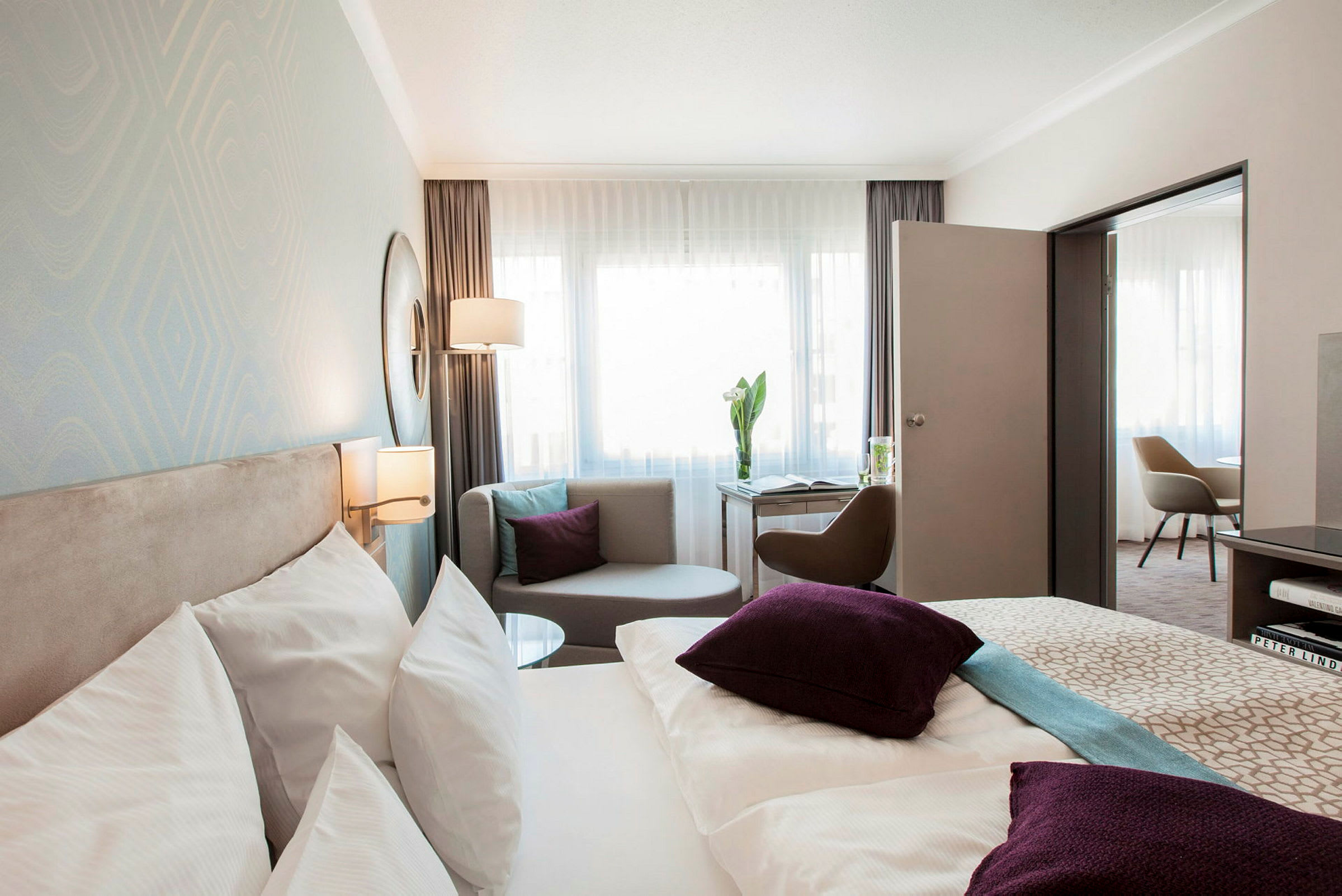Kuva hotellihuoneesta, jossa sänky, istumapaikka ja kirjoituspöytä. (Tekoälyn luoma teksti)