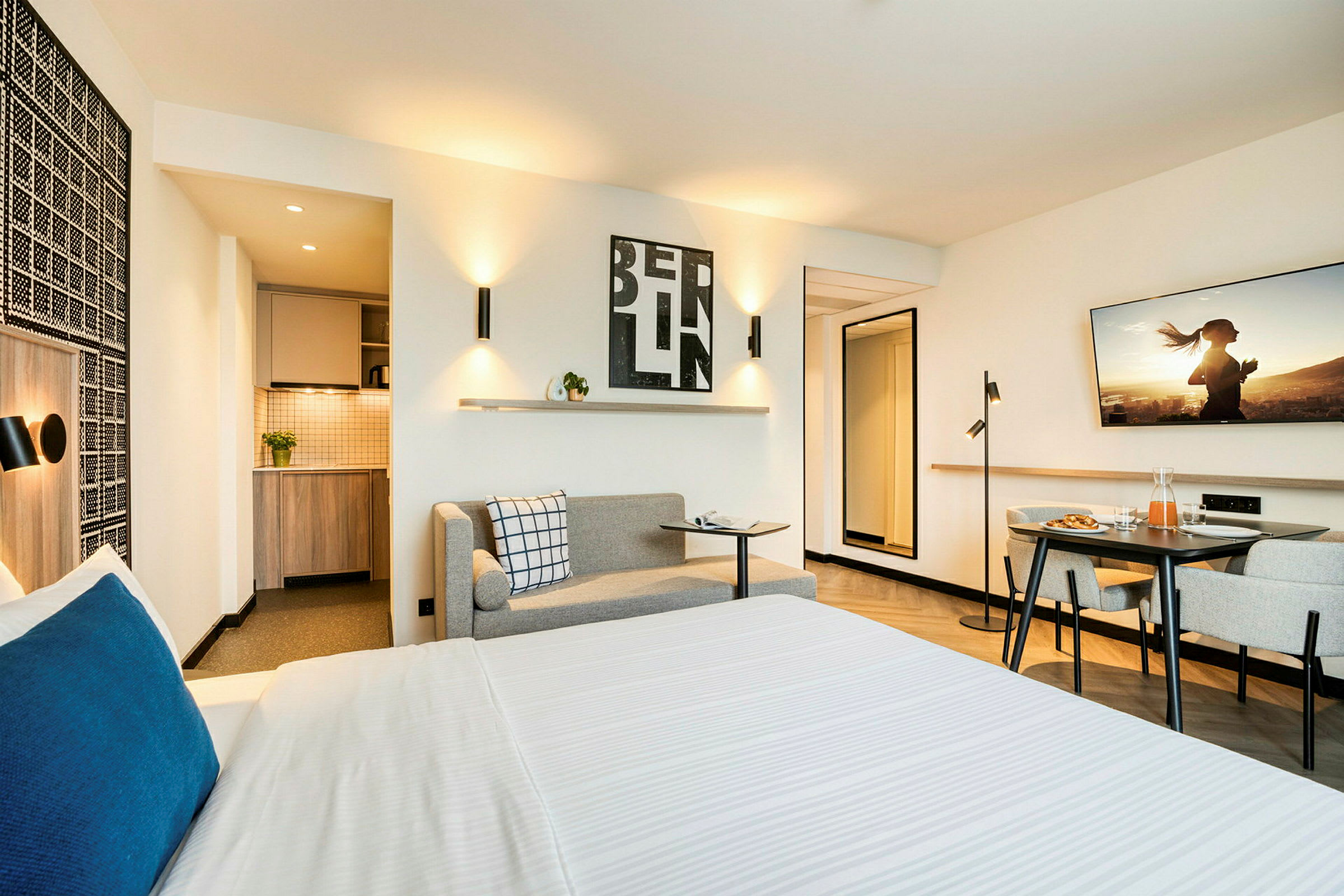 Modernin hotellihuoneen sisätilat, jossa sänky, pieni keittokomero ja istuinryhmä. (Tekoälyn luoma teksti)