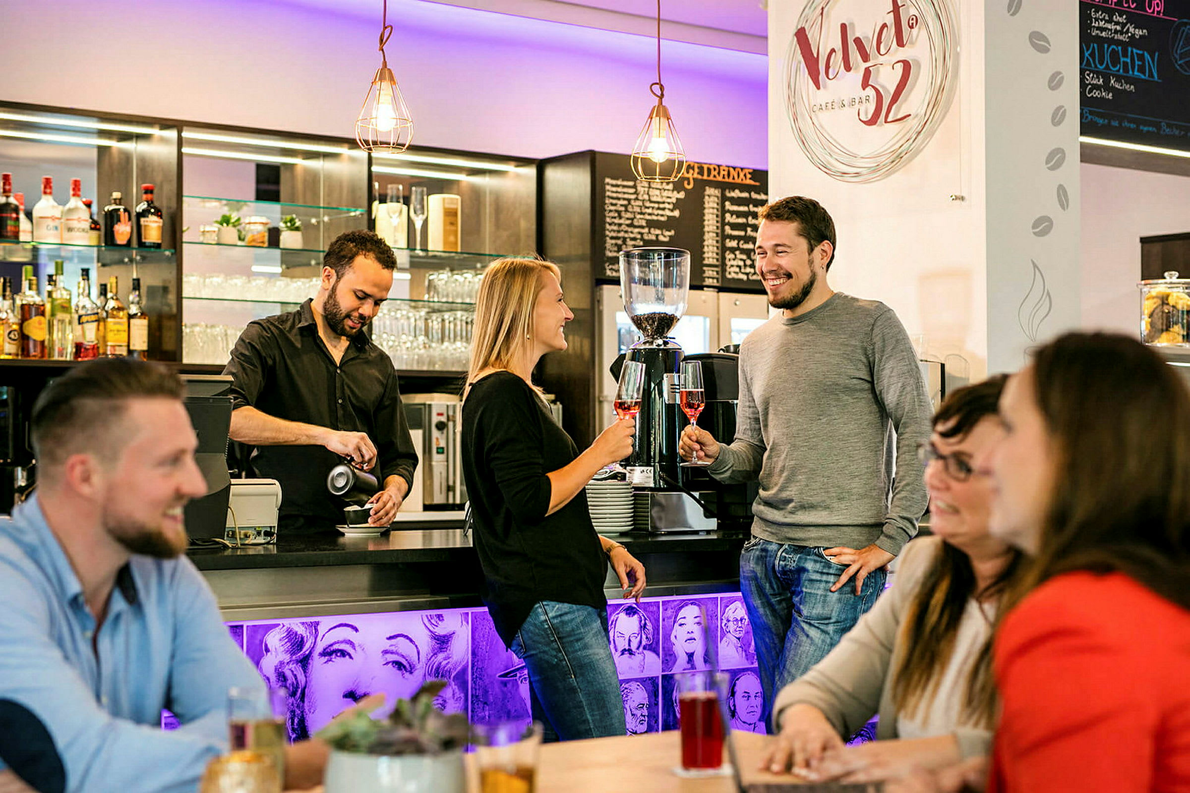 Barista kaataa kahvia baaritiskillä, jossa ihmiset seisovat ja istuvat nauttien juomistaan. (Tekoälyn luoma teksti)