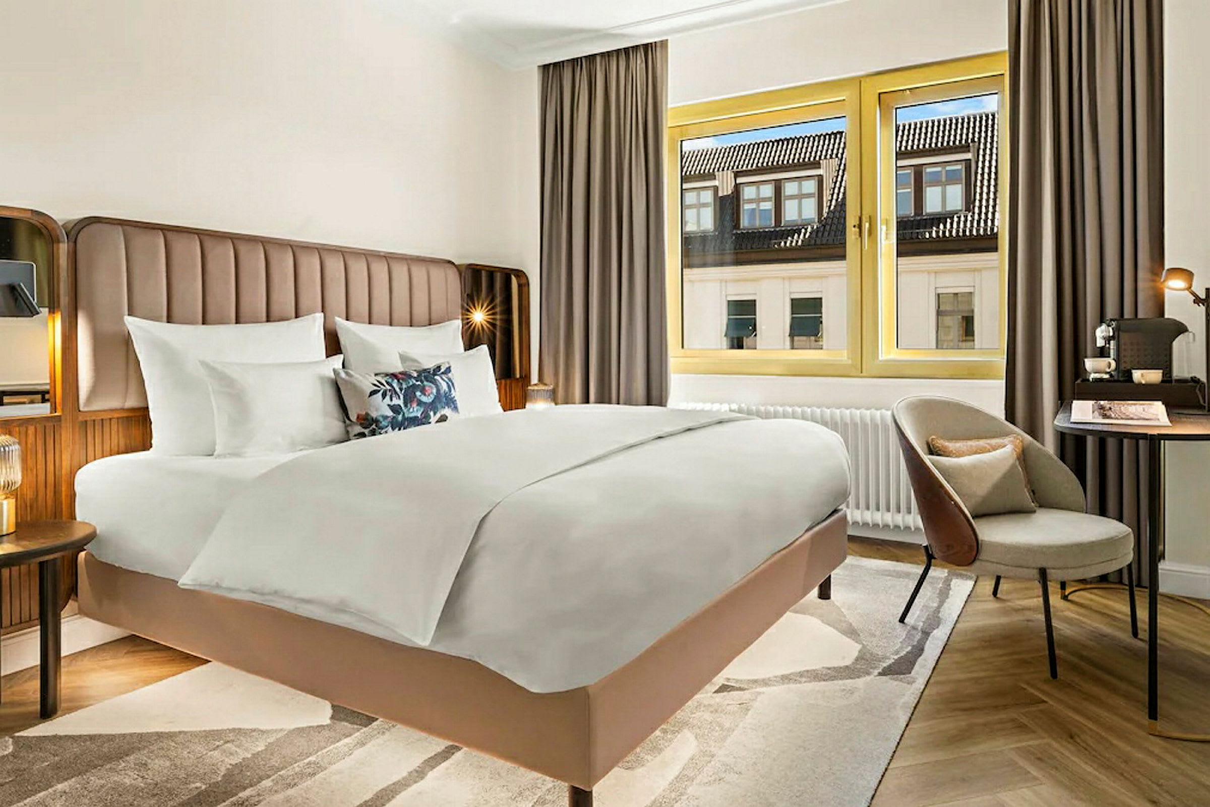Hotellihuone, jossa on suuri sänky, ikkuna näkymällä ja kirjoituspöytä. (Tekoälyn luoma teksti)