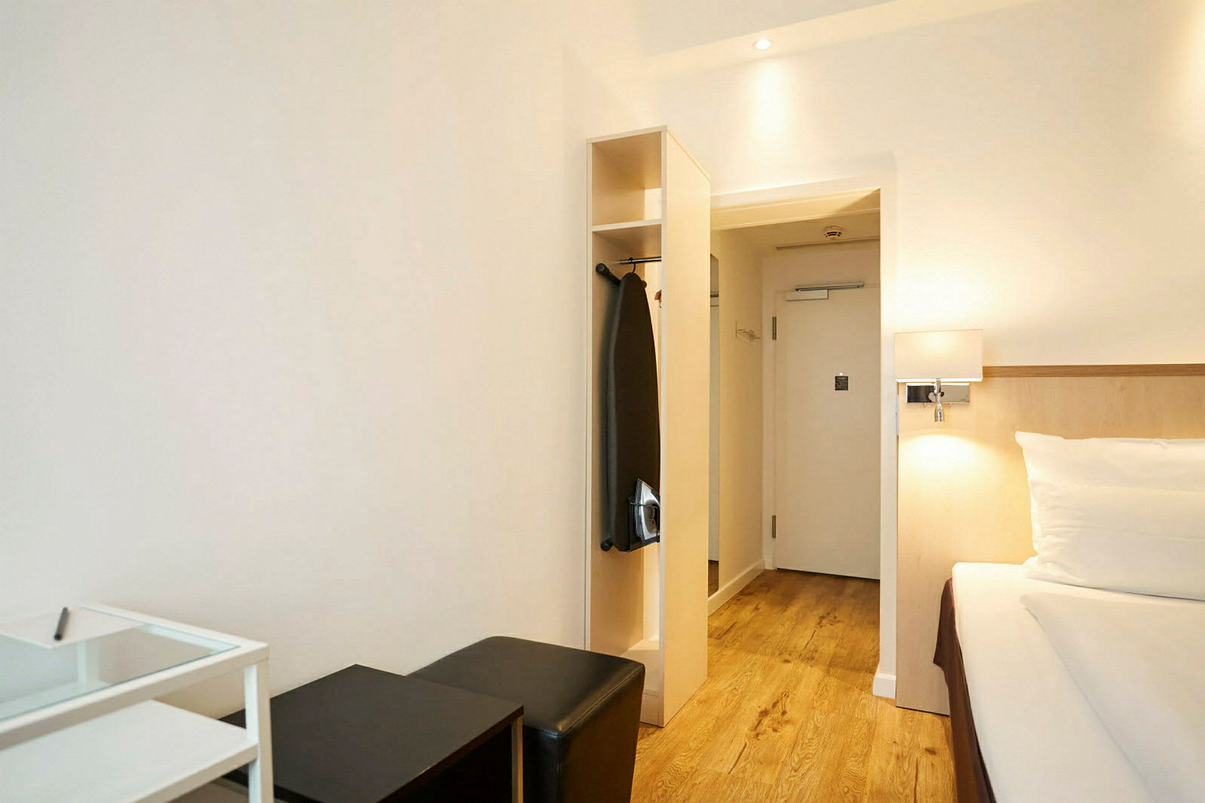 Hotellihuone, jossa on sänky, istuimia ja vaatekaappi. (Tekoälyn luoma teksti)