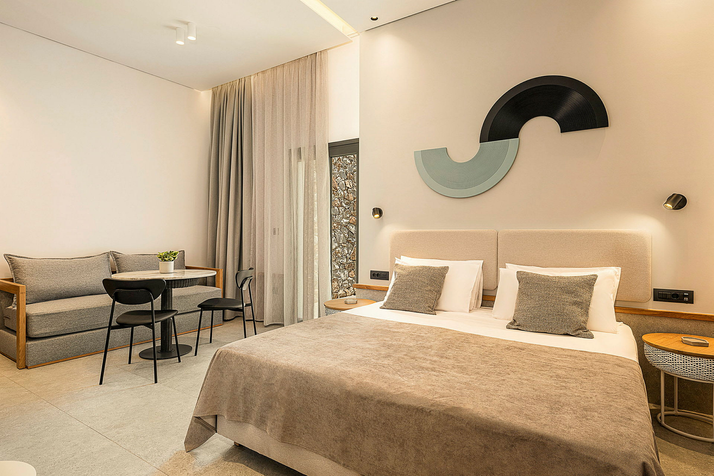 Moderni hotellihuone, jossa on parisänky, oleskeluryhmä ja koristeellisia yksityiskohtia. (Tekoälyn luoma teksti)