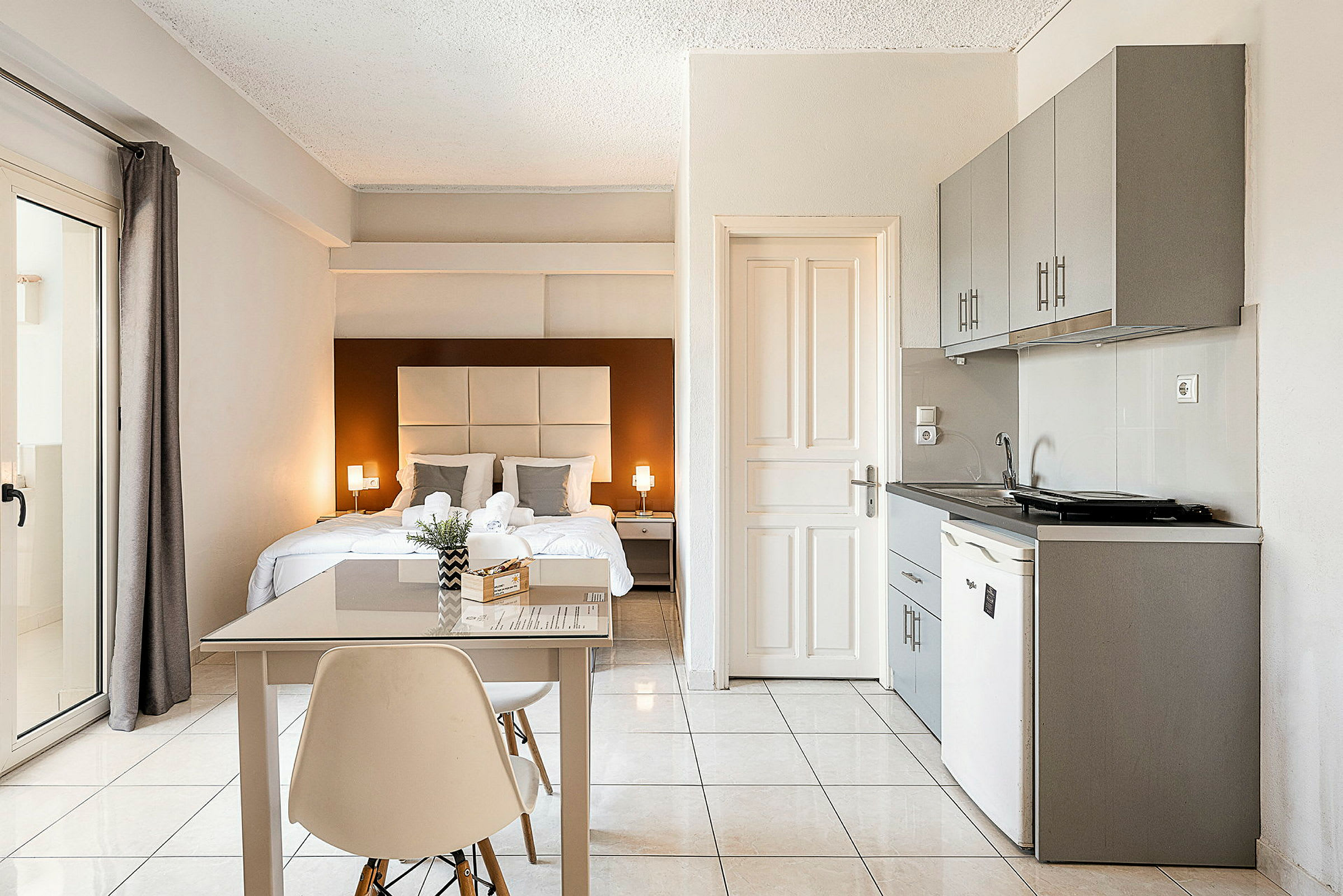 Valoisa ja moderni hotellihuone, jossa on parivuode, pieni ruokapöytä ja keittokomero. (Tekoälyn luoma teksti)