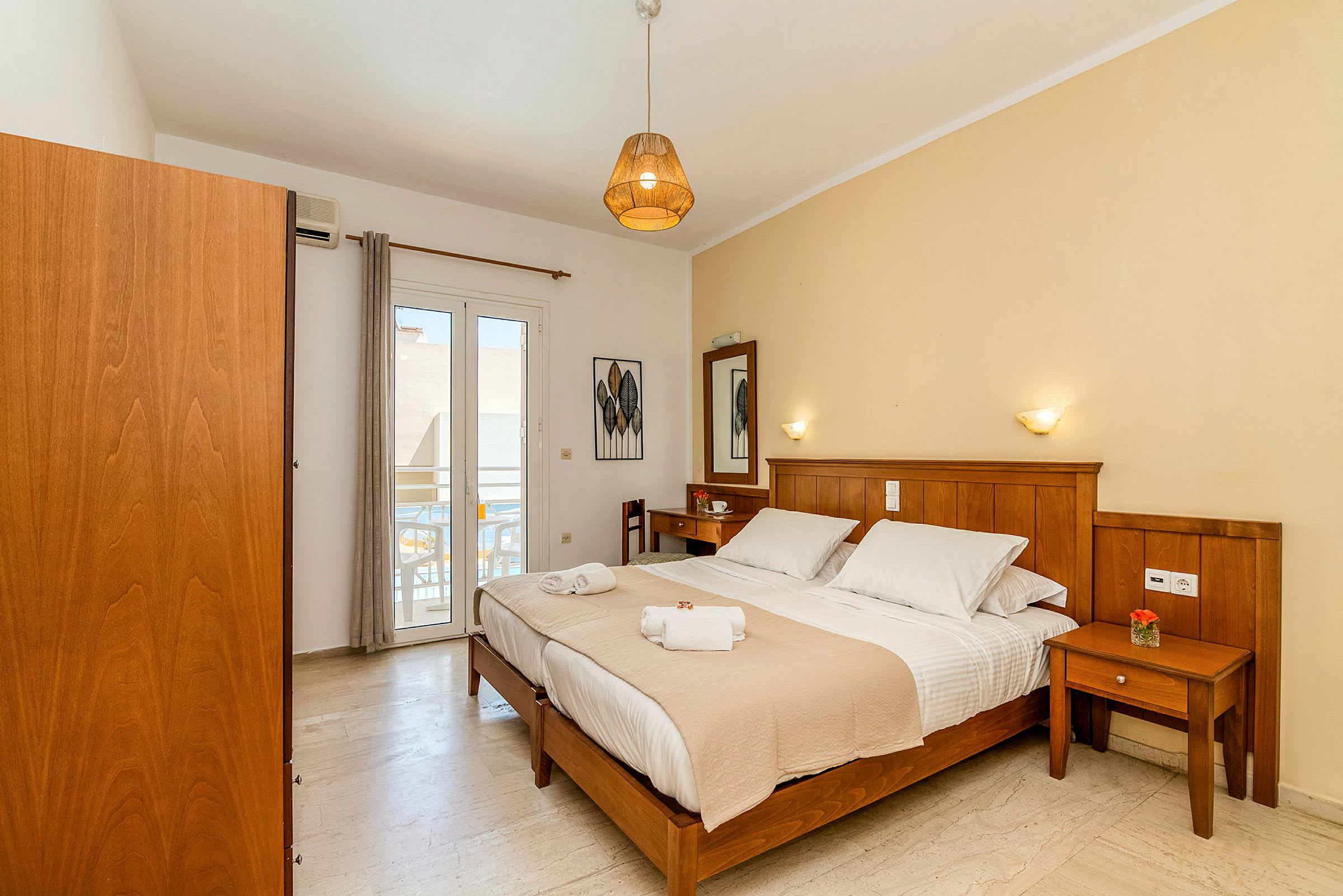 Hotellihuone, jossa on parivuode, puukalusteet ja pieni parveke. (Tekoälyn luoma teksti)
