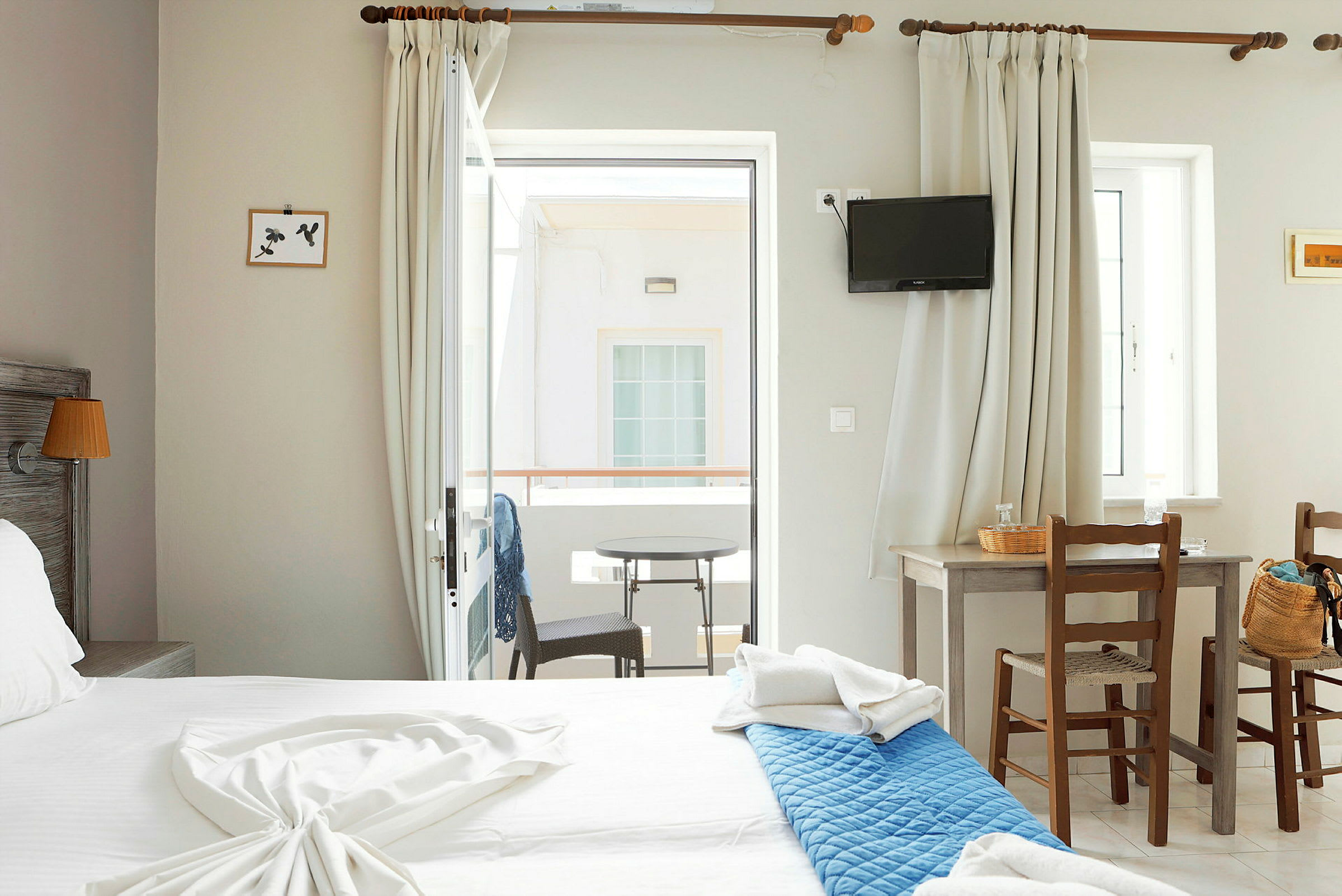 Hotellihuoneen sisustus, jossa parivuote, pöytä kahdella tuolilla ja parveke näkymällä. (Tekoälyn luoma teksti)