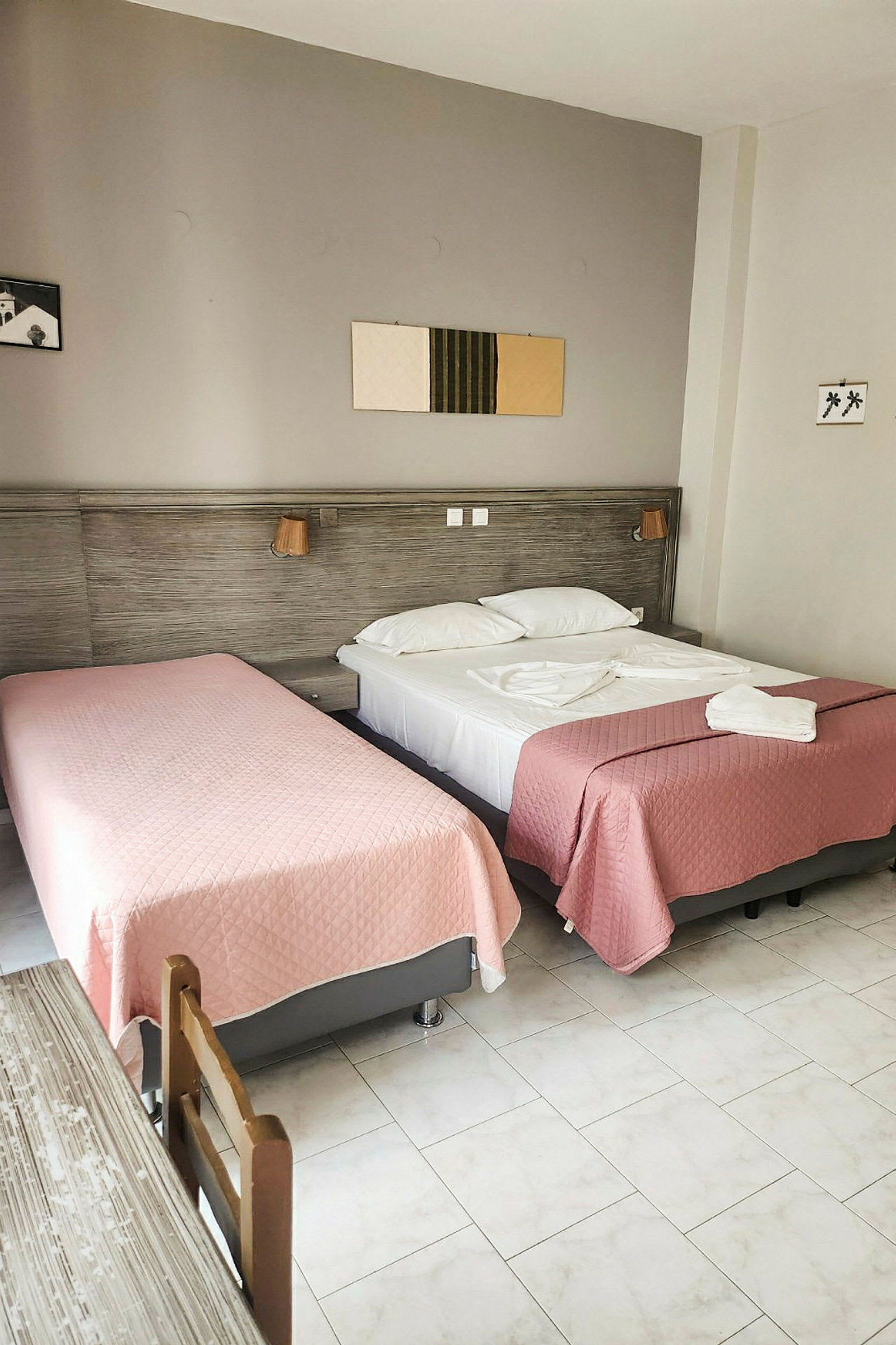 Hotellihuone, jossa kaksi sänkyä vaaleanpunaisilla päiväpeitteillä. (Tekoälyn luoma teksti)