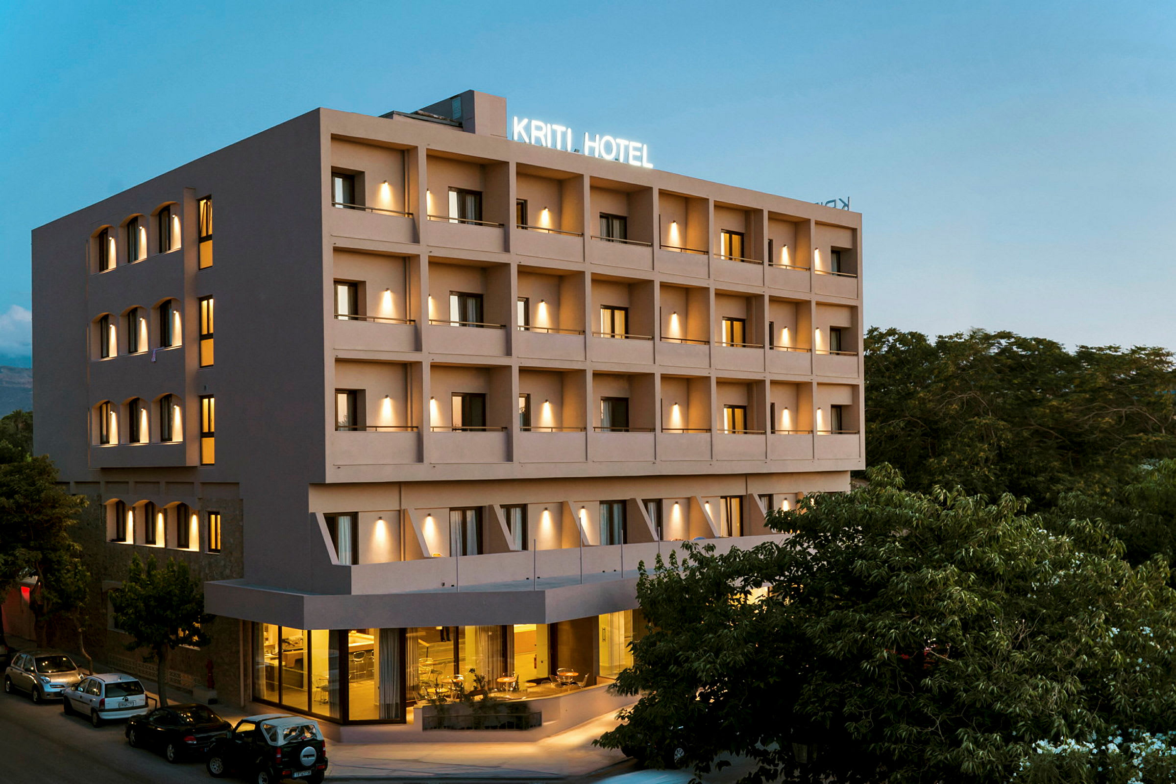 Usean kerroksen hotellirakennus, valaistus ja pysäköinti sisäänkäynnin edessä. (Tekoälyn luoma teksti)