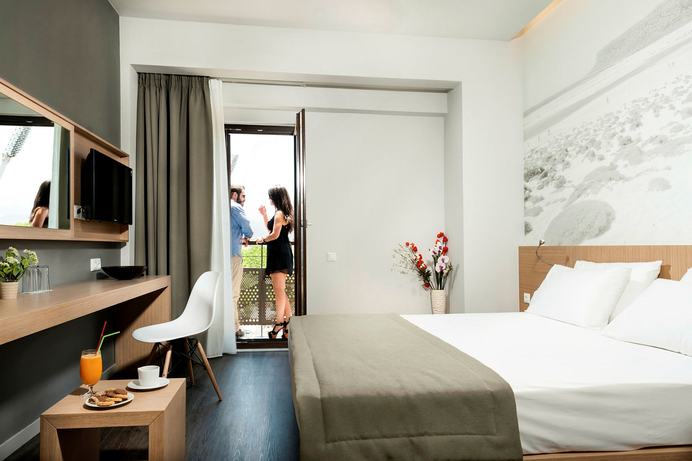 Moderni hotellihuone, jossa parivuode, työpöytä ja näkymä parvekkeelle. (Tekoälyn luoma teksti)