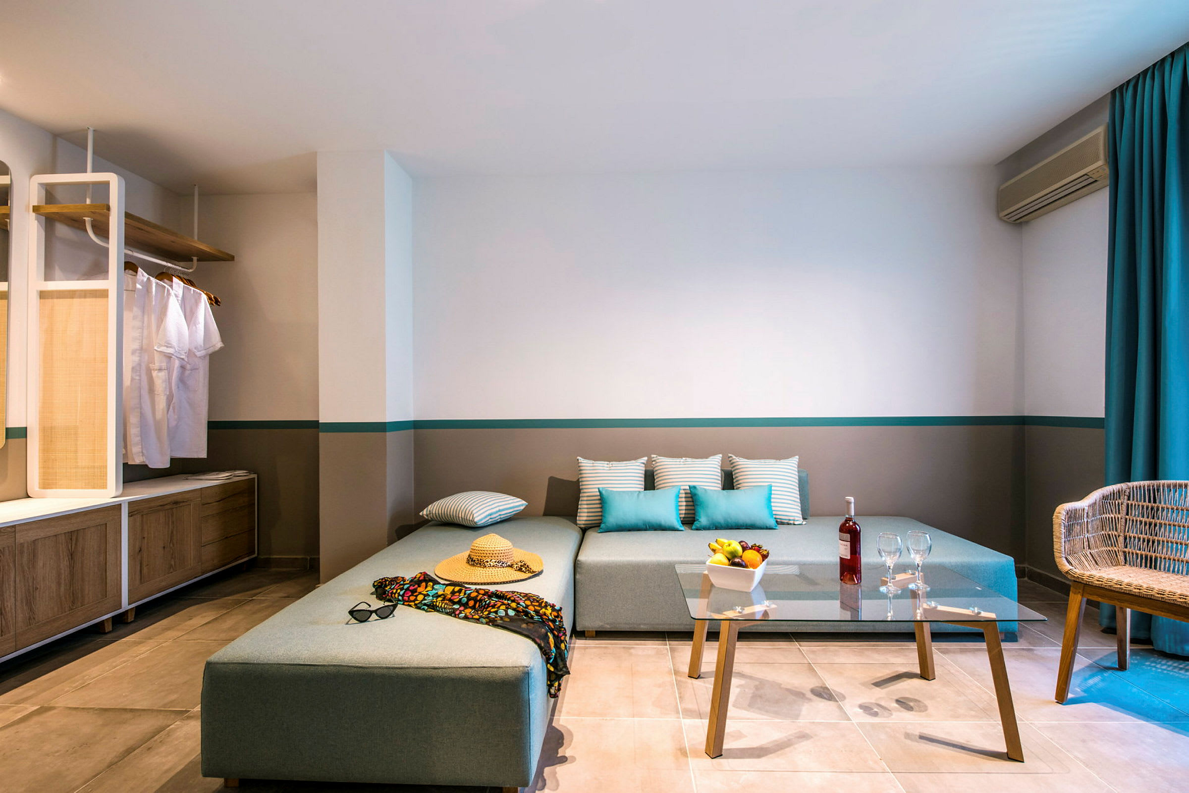 Moderni hotellihuone kulmasohvalla, lasisella sohvapöydällä ja rentouttavalla sisustuksella. (Tekoälyn luoma teksti)