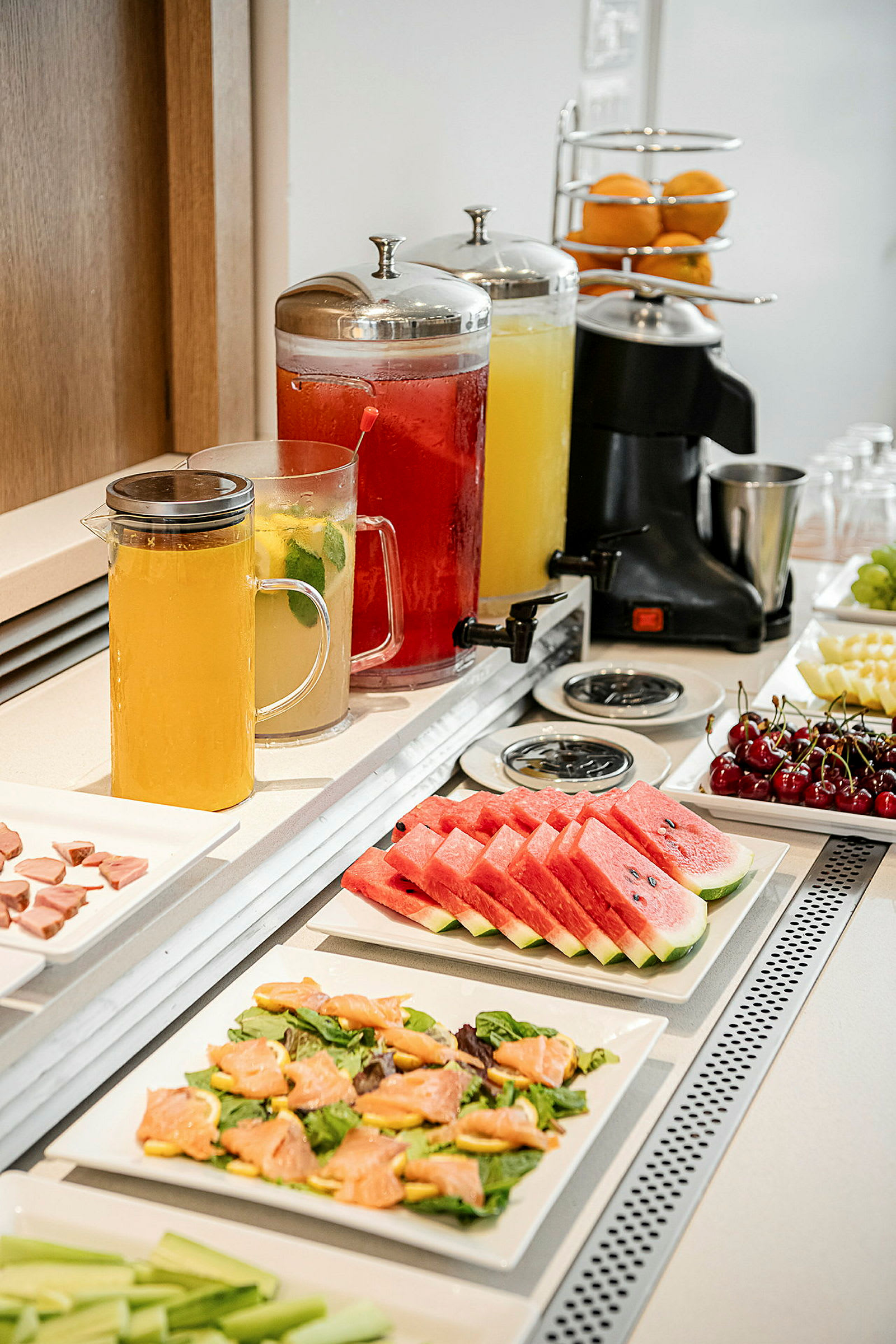 Buffet, jossa hedelmäviipaleita, salaattiannoksia ja kannuja juomilla. (Tekoälyn luoma teksti)
