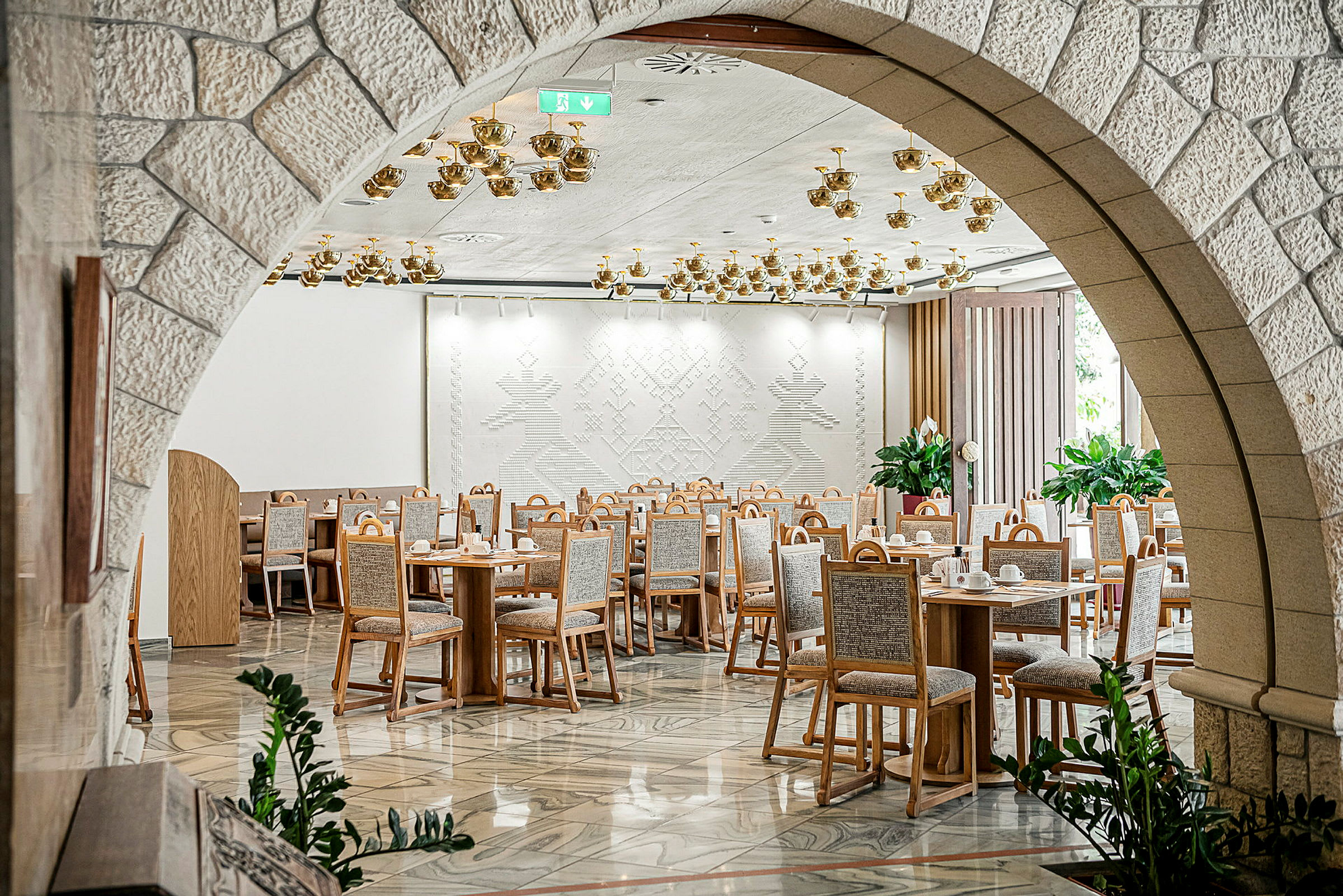 Ravintola, jossa pöydät ja tuolit on asetettu koristeelliseen odotushuoneeseen. (Tekoälyn luoma teksti)