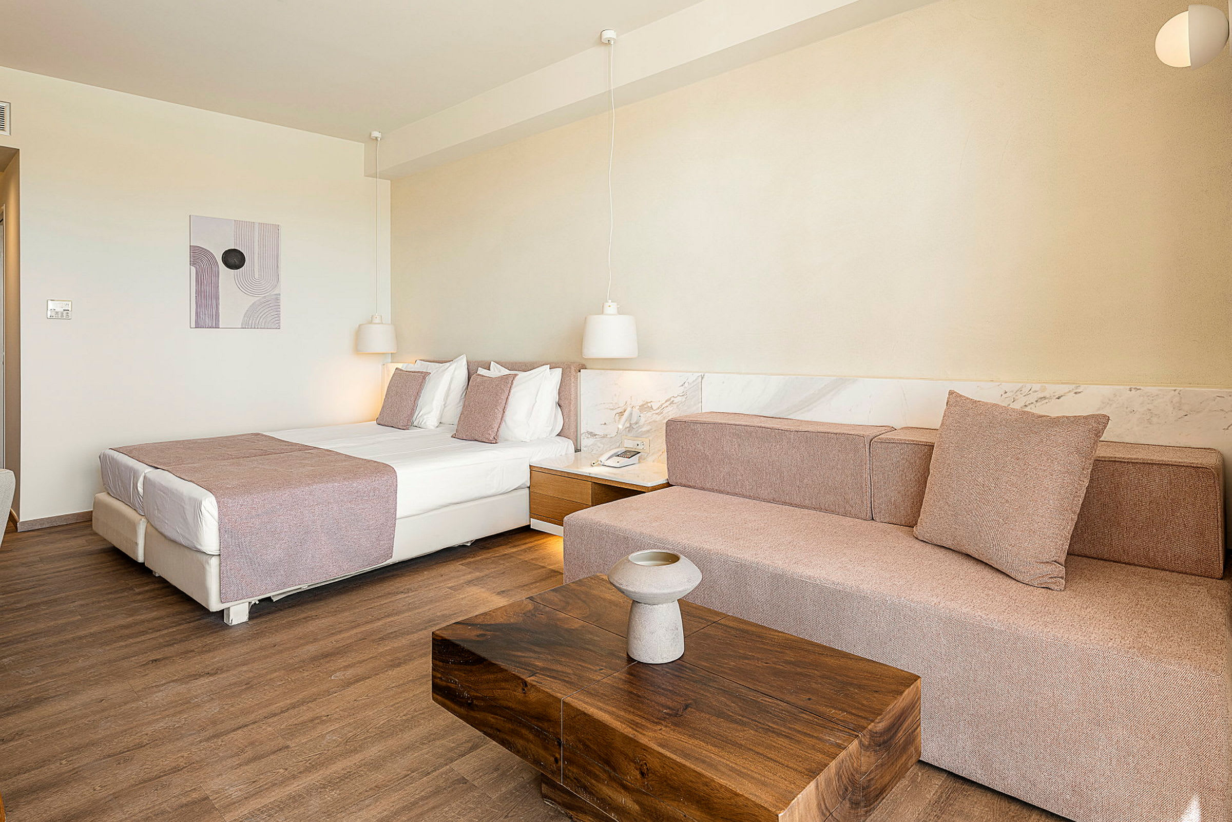 Hotellihuone, jossa on sänky, sohva ja puupöytä. (Tekoälyn luoma teksti)