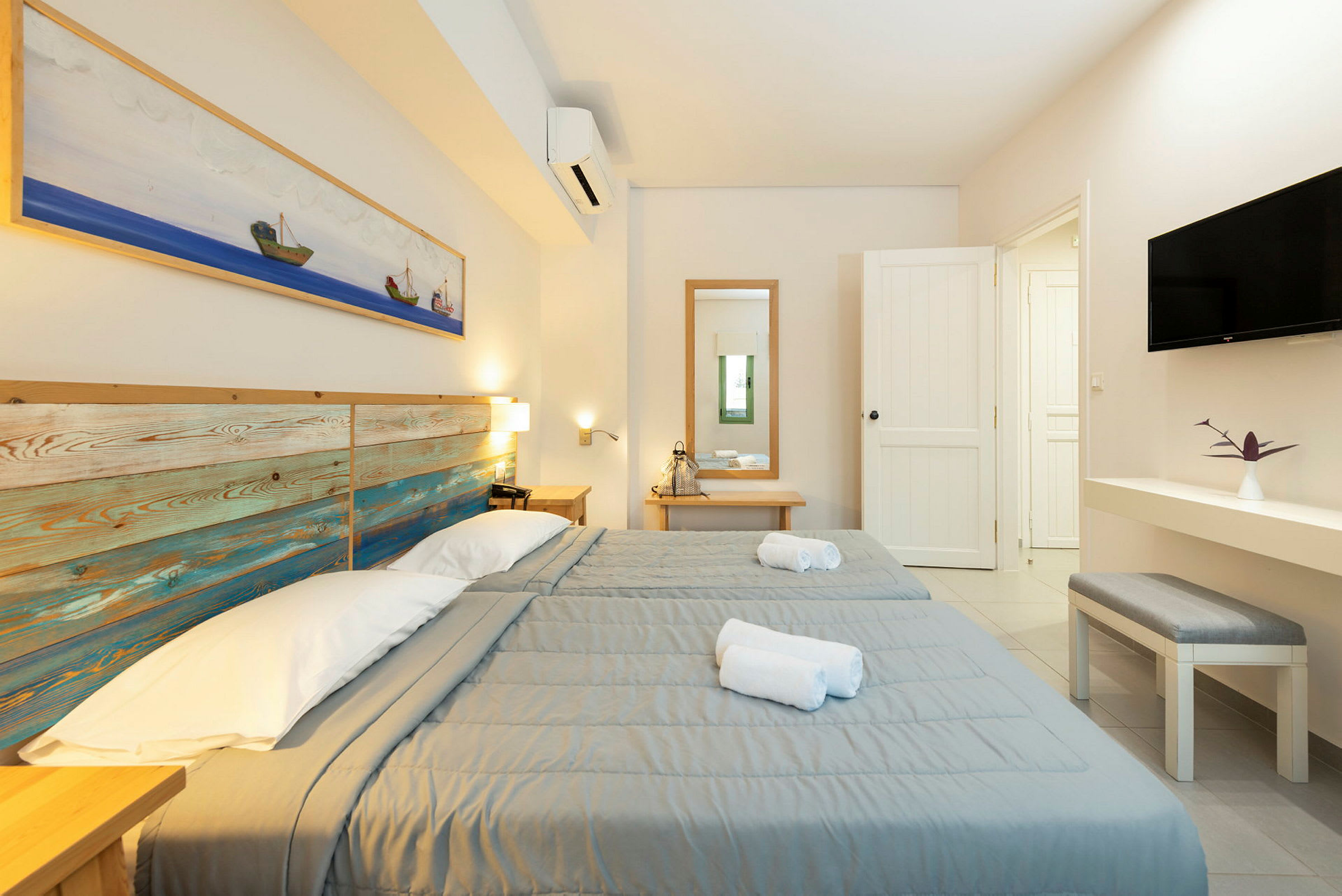 Kaksi erillistä sänkyä harmailla päiväpeitteillä vaaleassa hotellihuoneessa. (Tekoälyn luoma teksti)