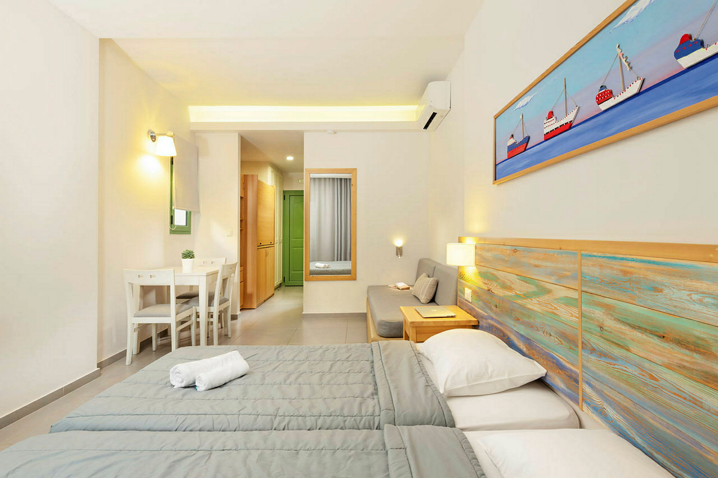 Hotellihuone, jossa on kaksi sänkyä, oleskelutila ja pieni ruokailutila. (Tekoälyn luoma teksti)