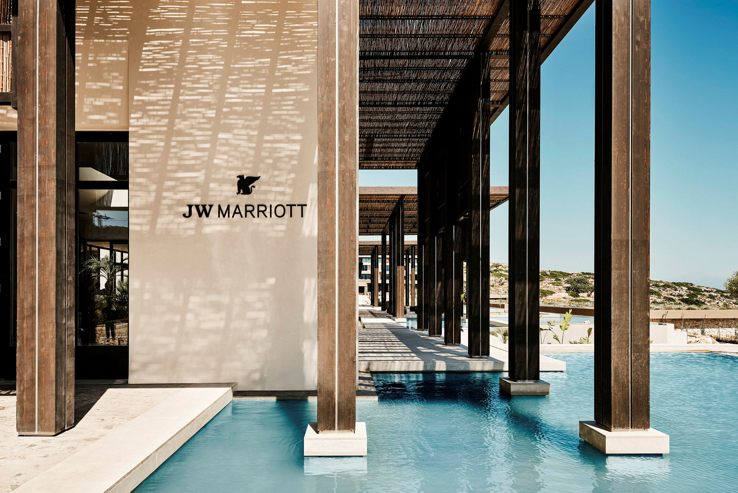 JW Marriott-logo vaalealla seinällä uima-altaan vieressä, jossa on puupylväitä. (Tekoälyn luoma teksti)