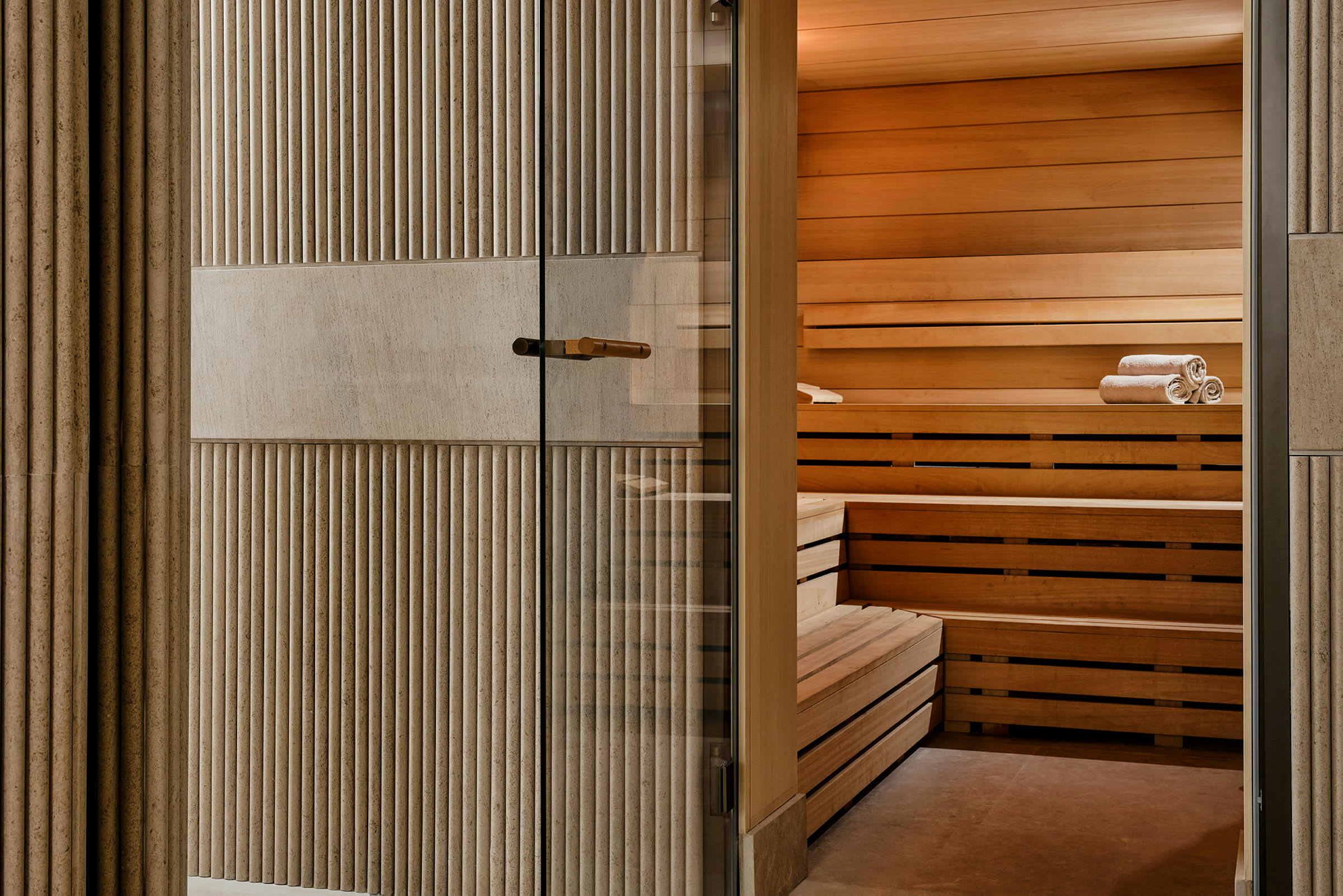 Sauna, jossa on puupaneeleja ja penkeille aseteltuja pyyhkeitä. (Tekoälyn luoma teksti)