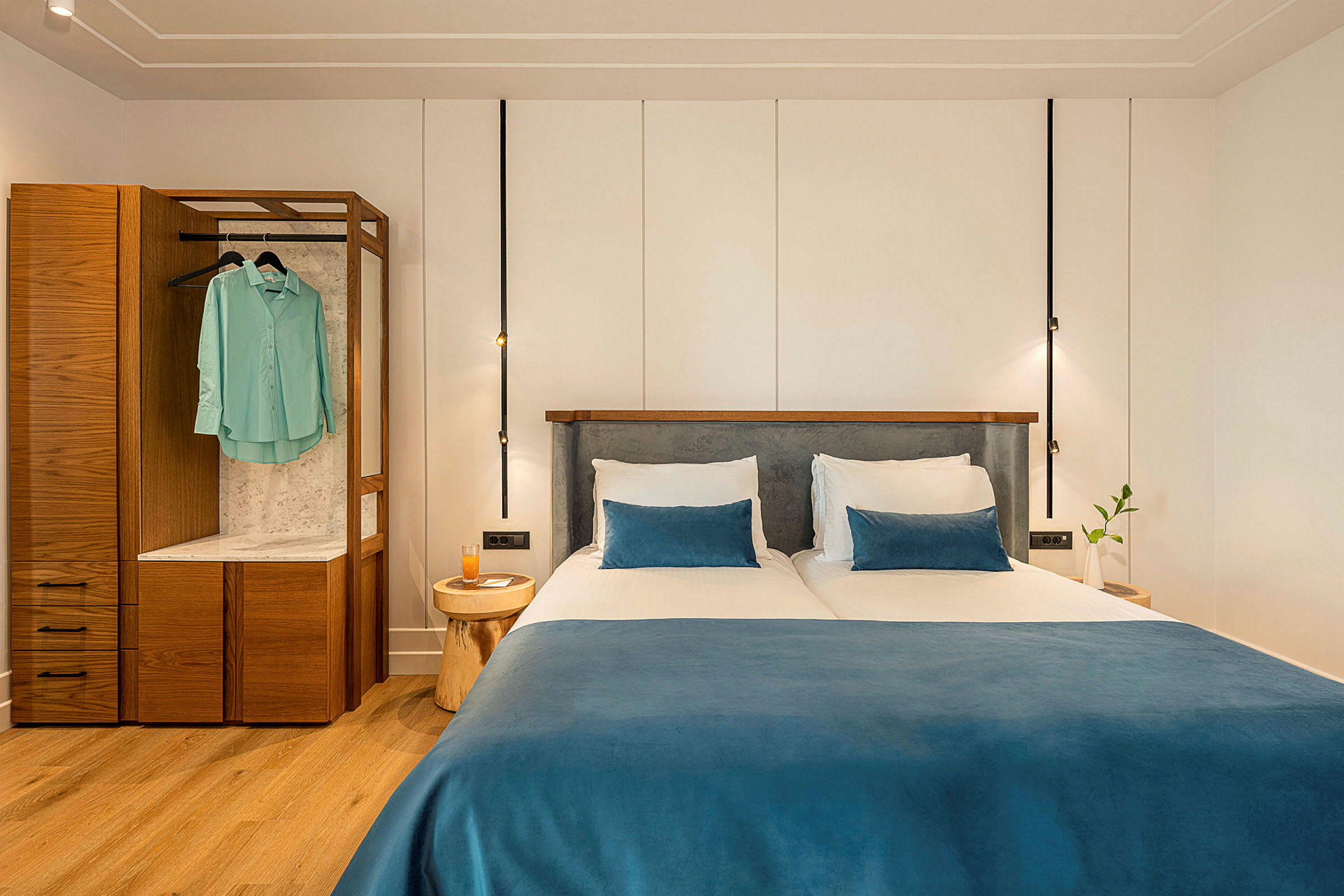 Kaksi yhden hengen vuodetta sinisillä päiväpeitteillä ja tyynyillä modernissa hotellihuoneessa. (Tekoälyn luoma teksti)