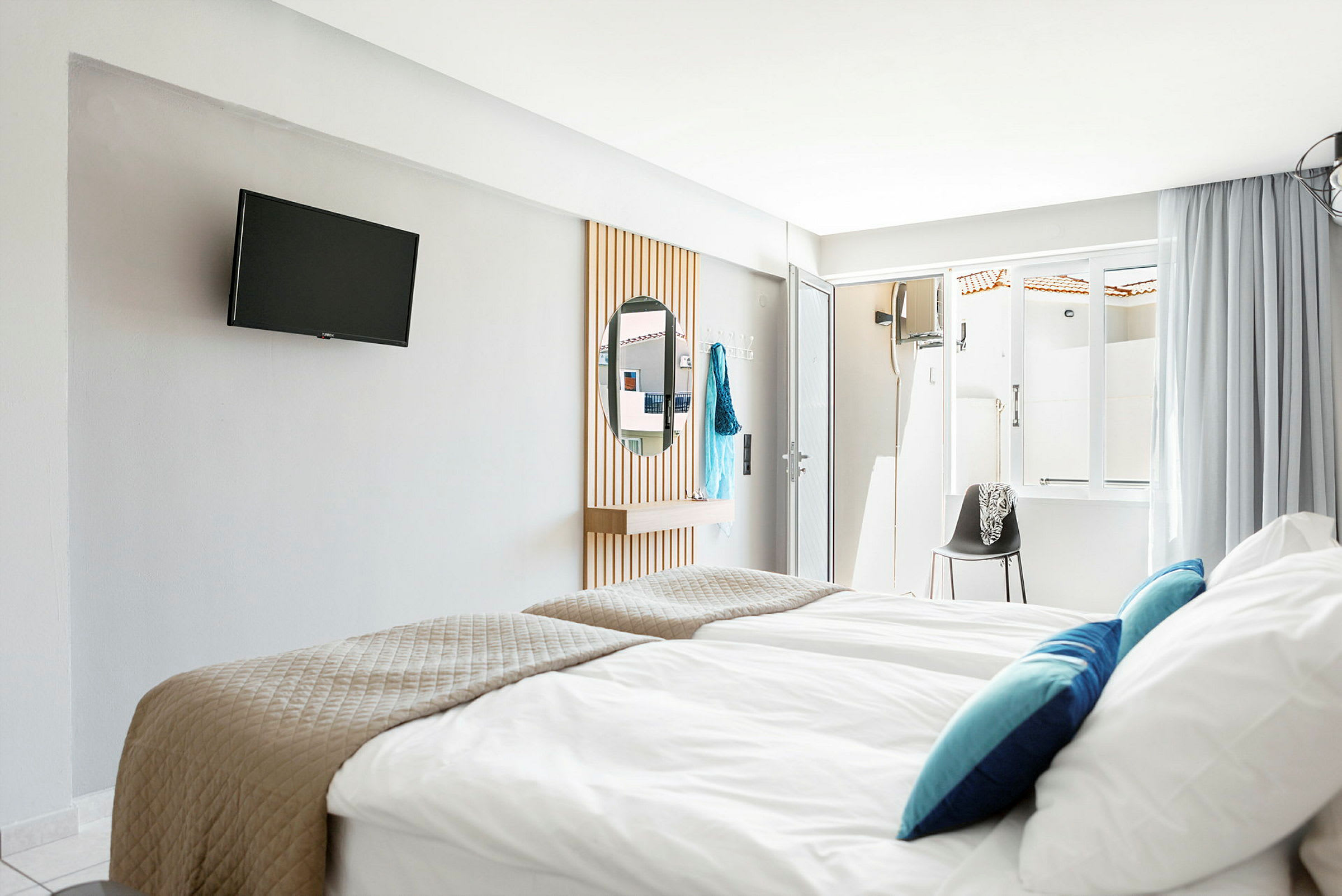 Hotellihuone, jossa vuoteet, TV seinällä ja peili. (Tekoälyn luoma teksti)