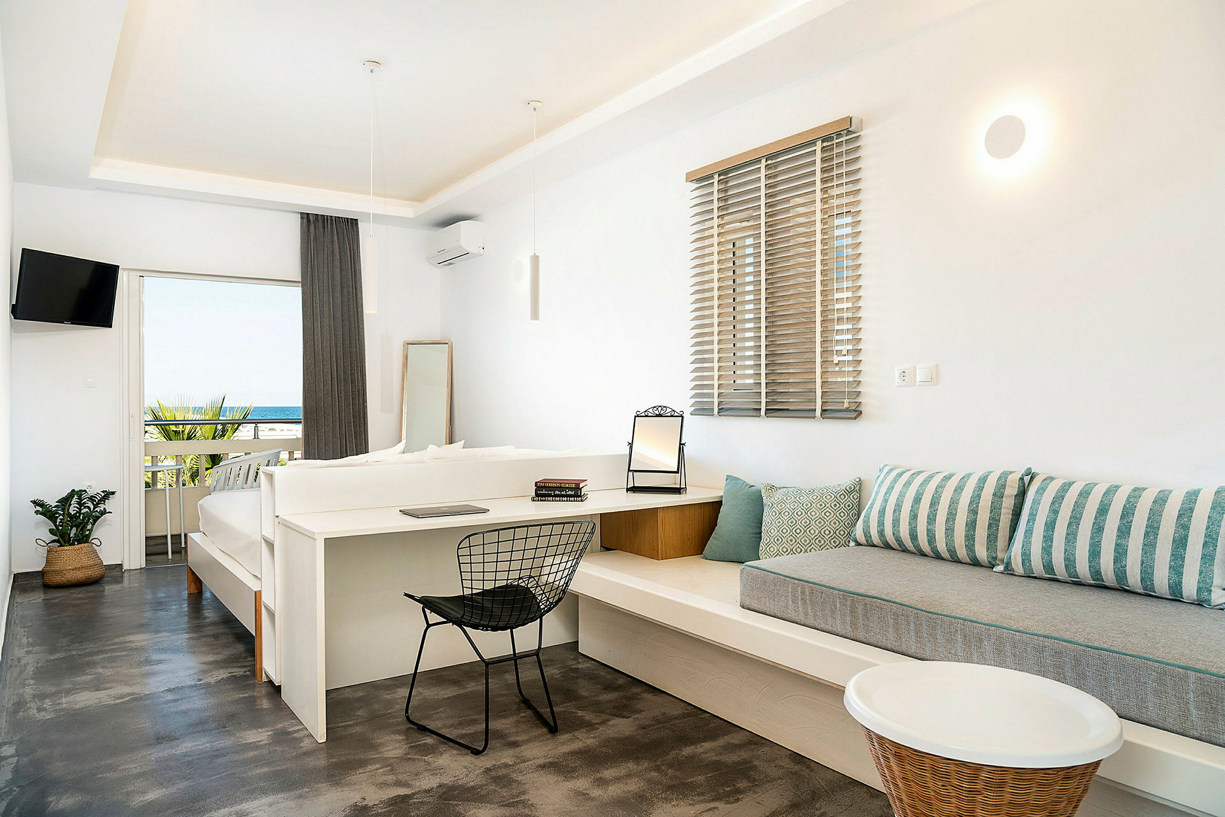 Hotellihuone vaalealla sisustuksella ja näkymä merelle parvekkeelta. (Tekoälyn luoma teksti)