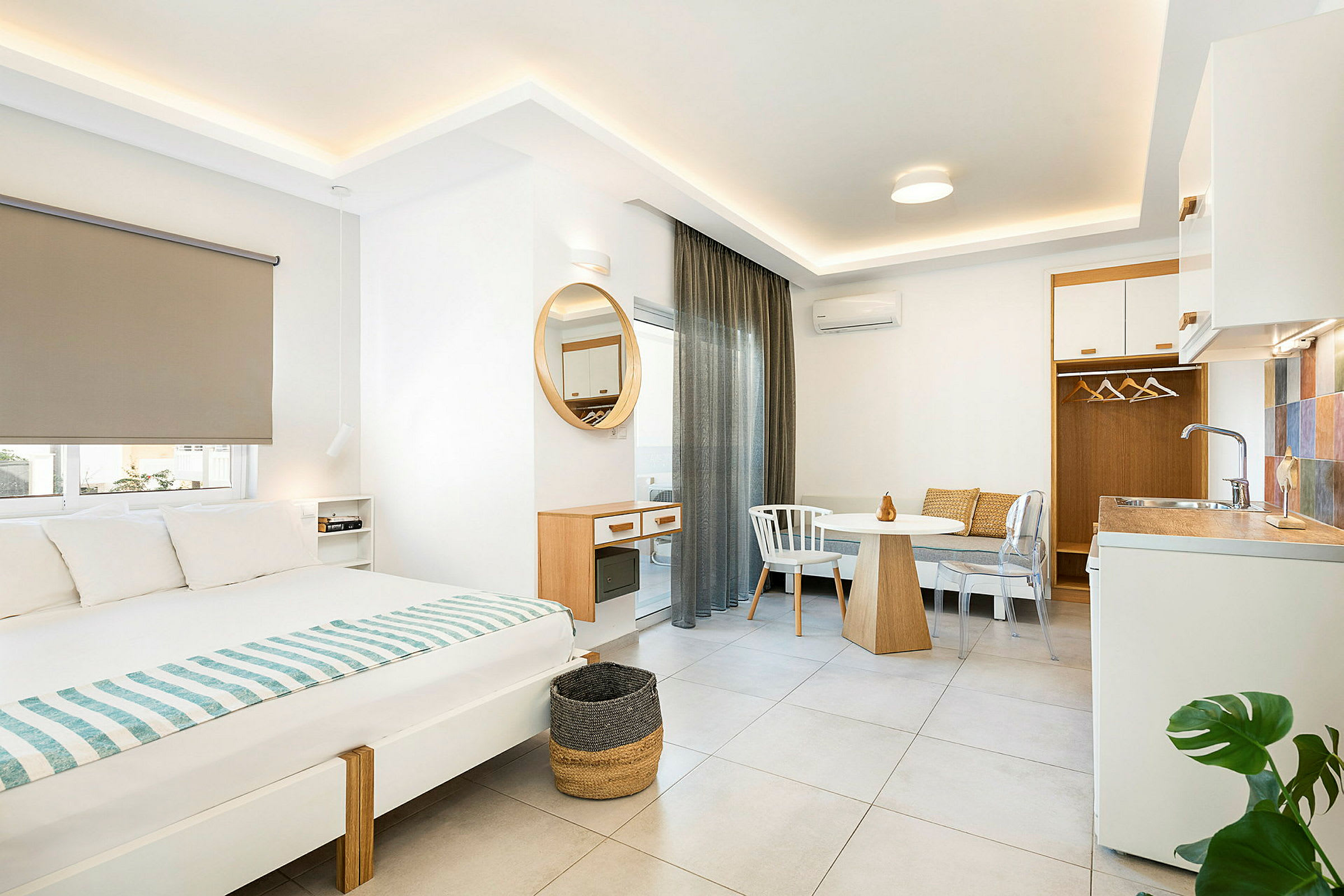 Moderni hotellihuoneen sisustus, jossa on sänky, ruokapöytä ja pieni keittiötila. (Tekoälyn luoma teksti)