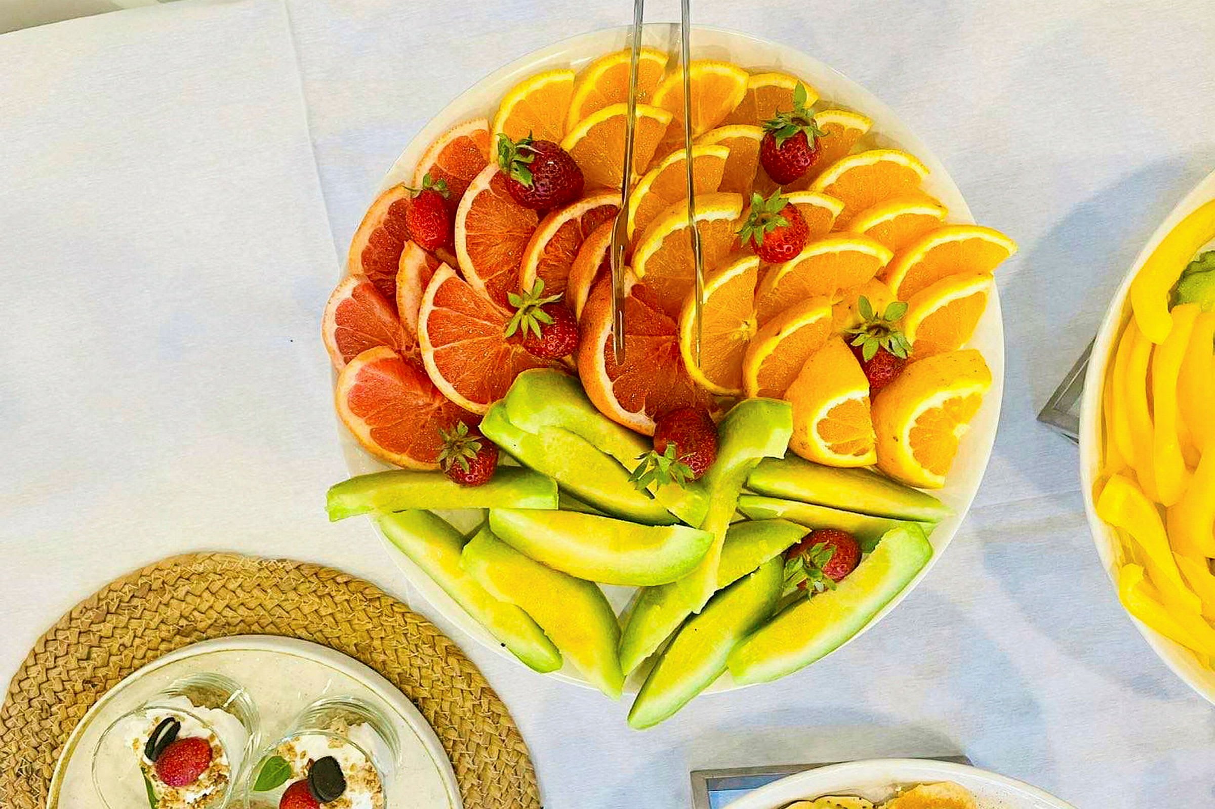 Lautasella viipaloituja hedelmiä, kuten greippiä, appelsiineja ja melonia, koristeltuna mansikoilla. (Tekoälyn luoma teksti)