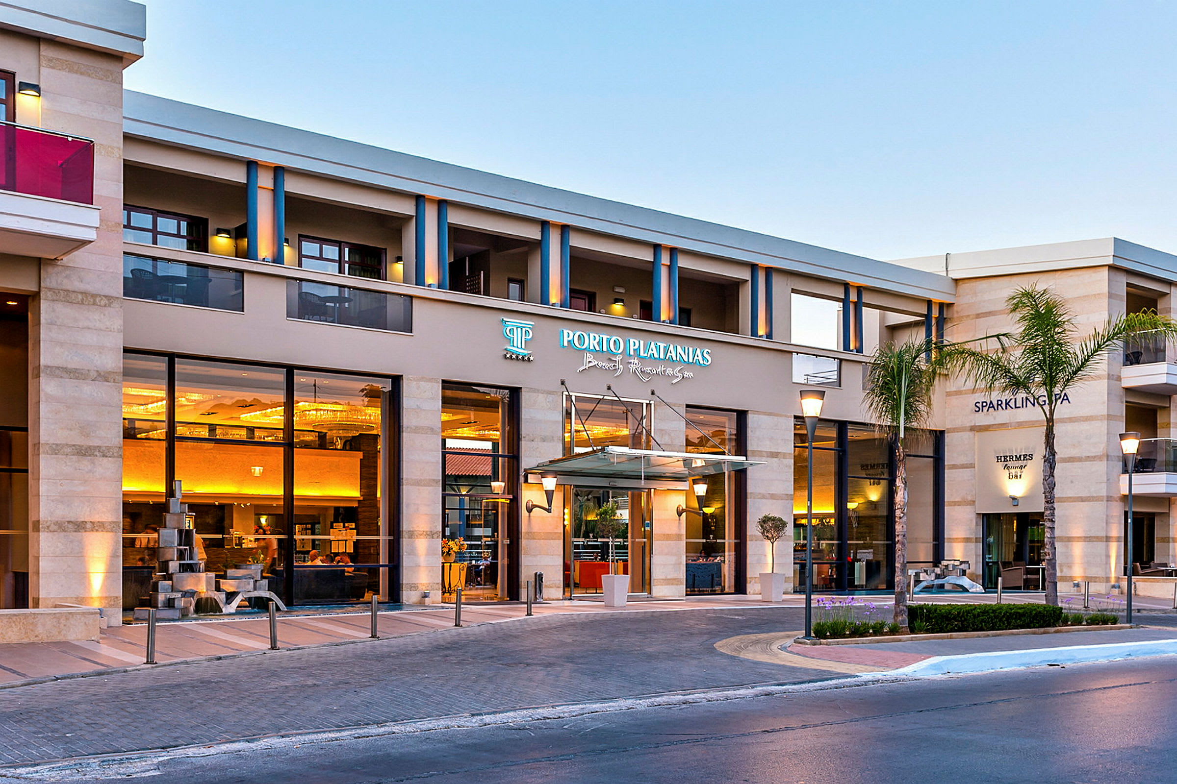 Hotellirakennus, jossa sisäänkäynnillä Porto Platanias Beach Resort & Spa -kyltti. (Tekoälyn luoma teksti)