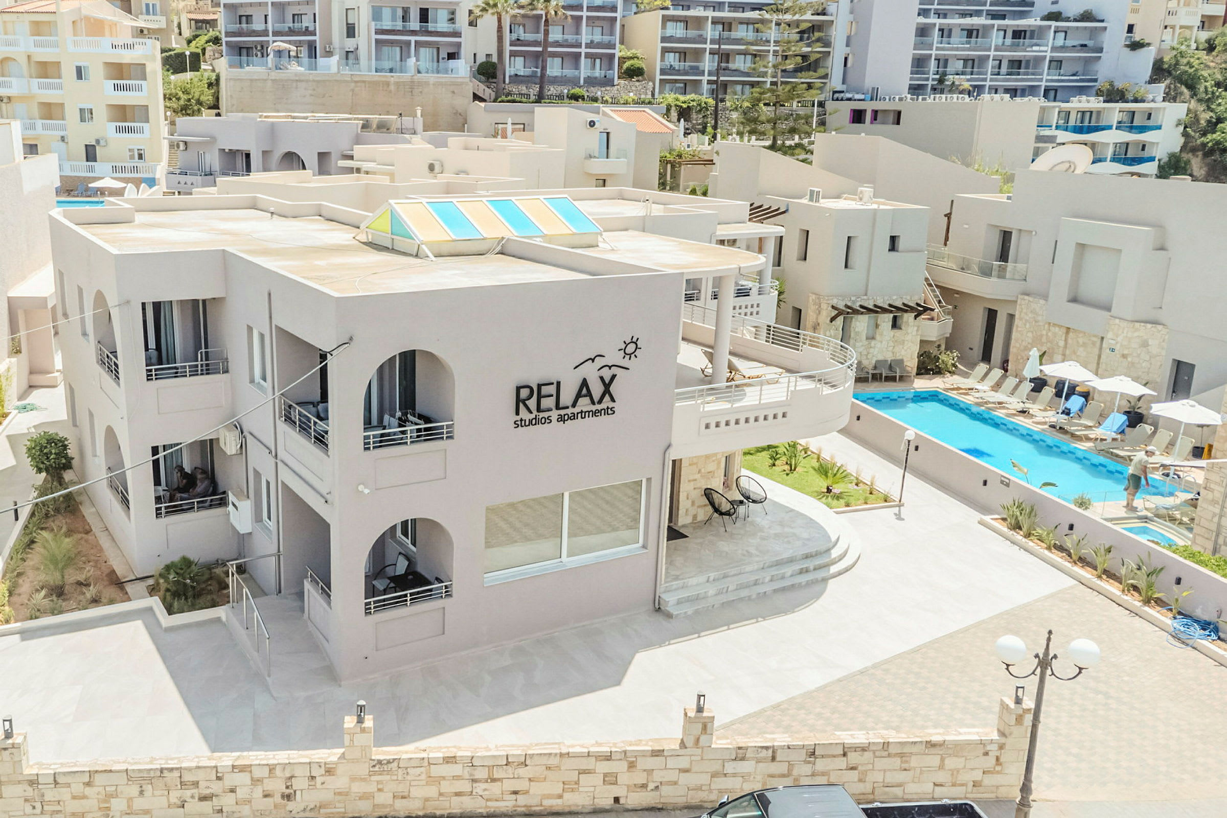 Relax Studios Apartmentsin ulkoalue, jossa on uima-allas ja aurinkotuoleja. (Tekoälyn luoma teksti)