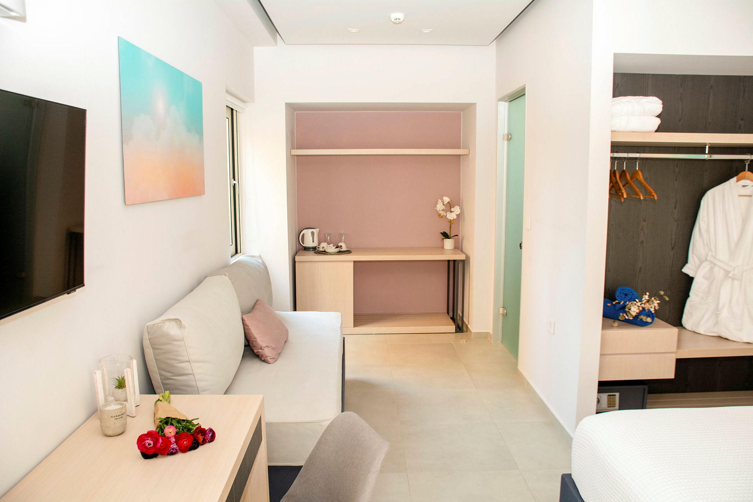 Moderni hotellihuone, jossa on sohva, pöytä ja vaatekaappi. (Tekoälyn luoma teksti)