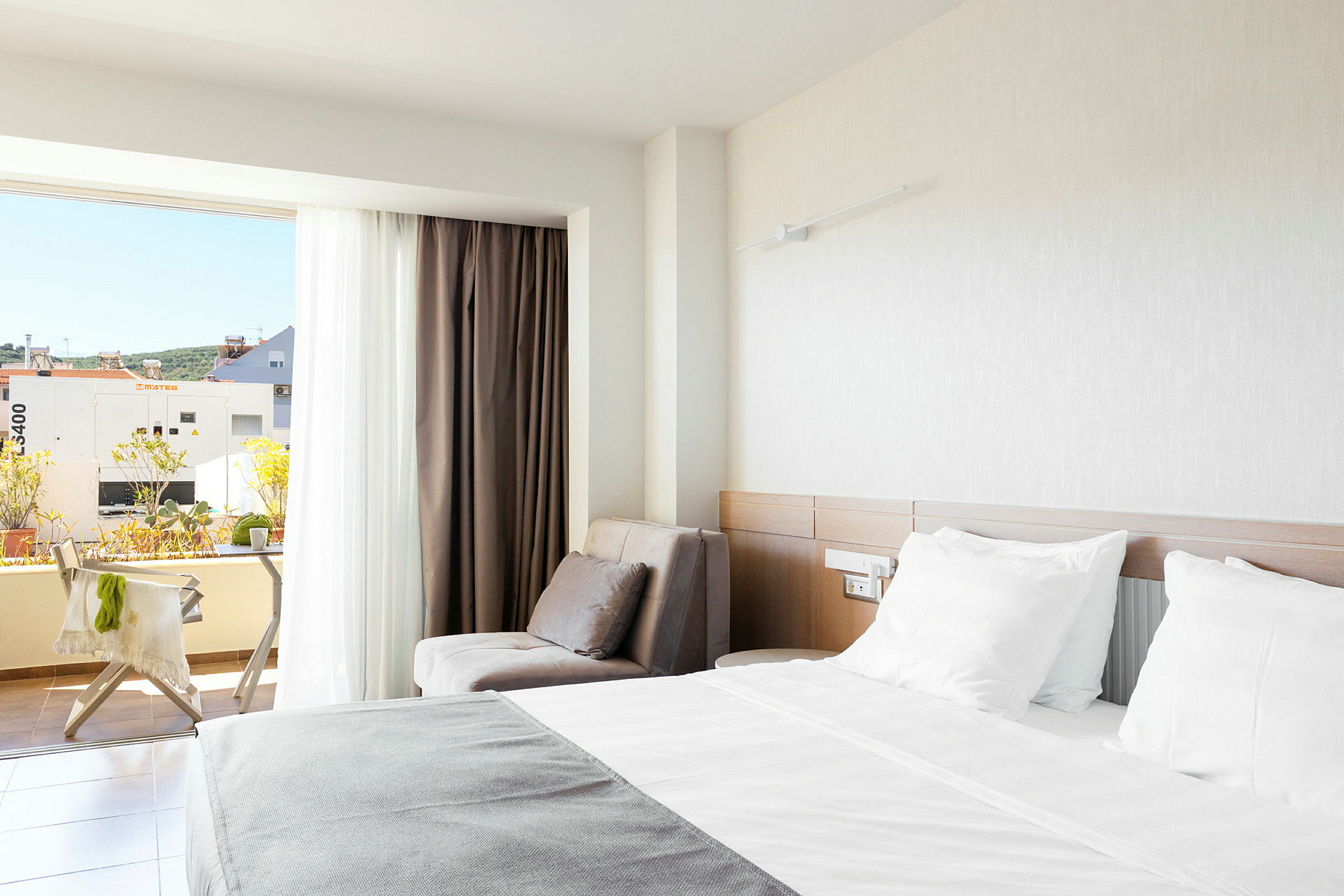 Hotellihuone, jossa parivuode, nojatuoli ja parveke näköalalla. (Tekoälyn luoma teksti)