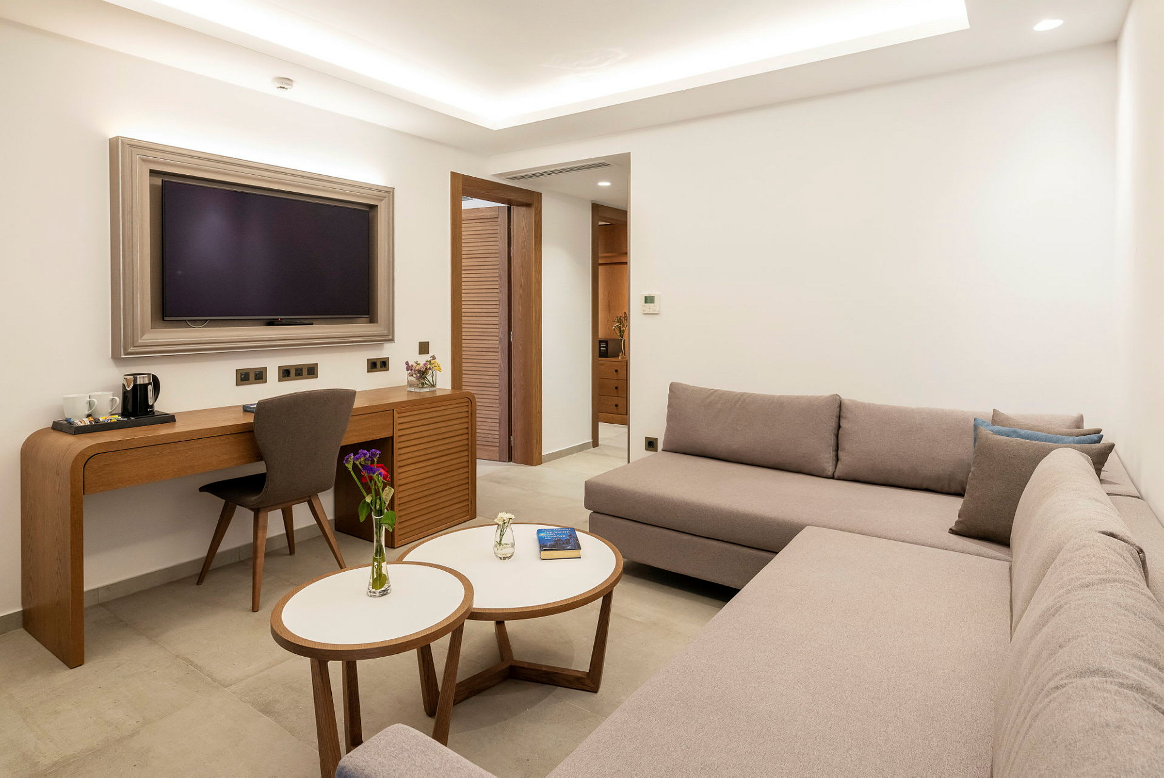 Moderni hotellihuone, jossa on sohva, kirjoituspöytä ja televisio. (Tekoälyn luoma teksti)
