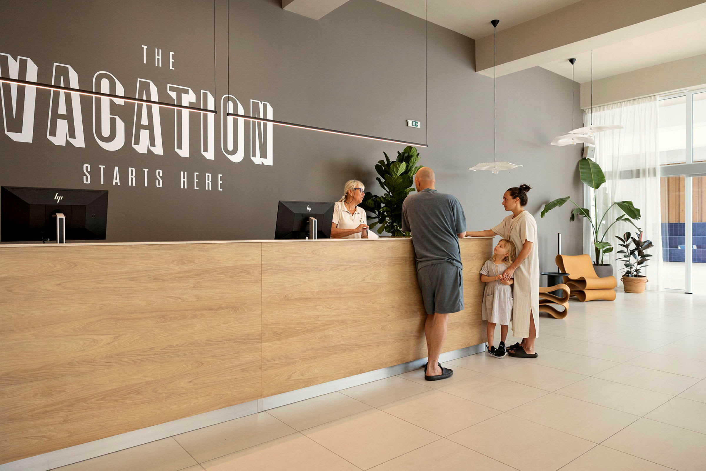 Vastaanotto, jossa on puinen tiski ja seinällä teksti "Vacation Starts Here". (Tekoälyn luoma teksti)